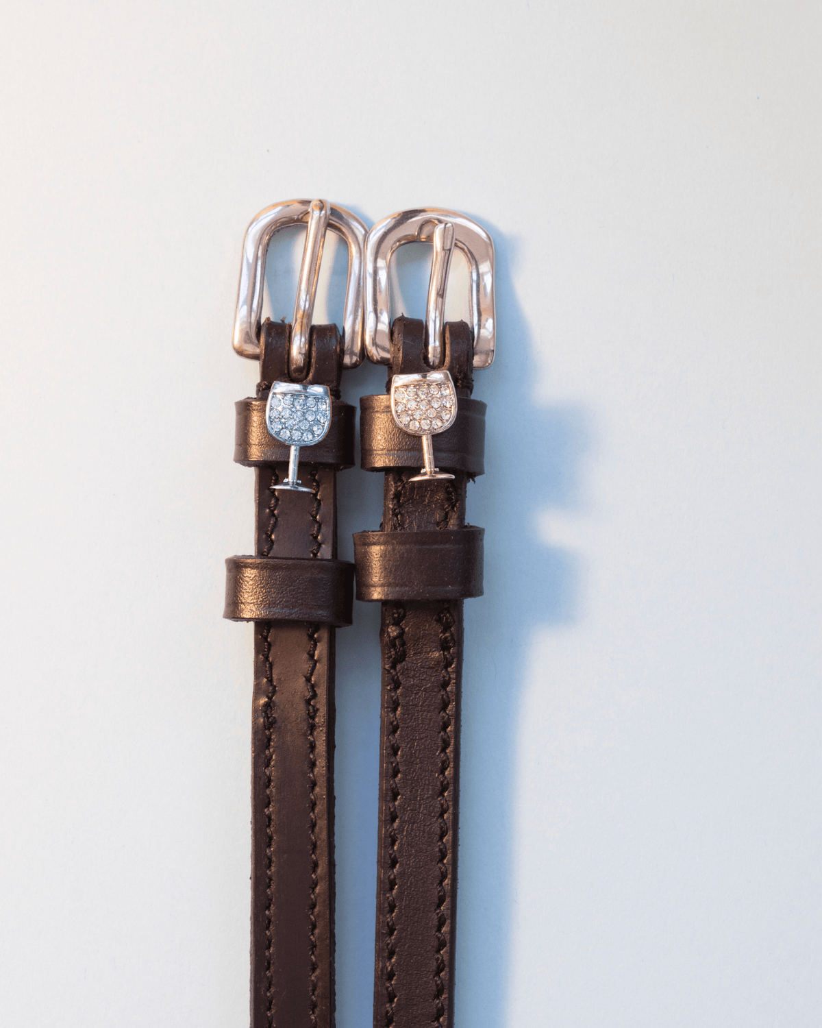 Brown leather crystal wine glass spur straps with rose gold buckles on pale grey