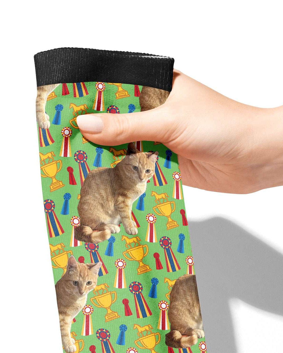 Hand holding custom green boot socks with cat and trophy pattern