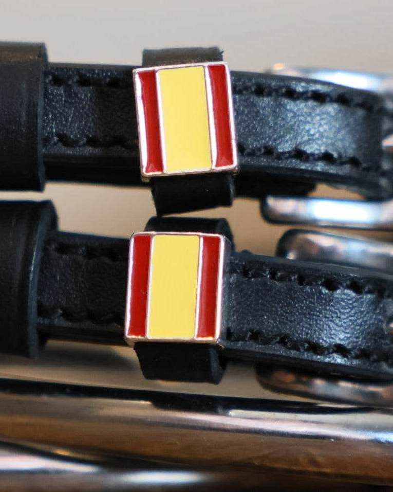 Close-up of Spain flag charms on black leather ManeJane spur strap keepers