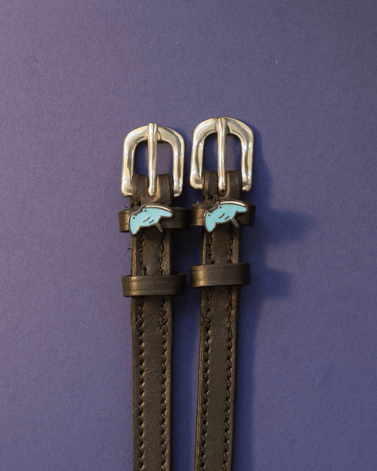Black leather stingray spur straps with blue stingray charms on an indigo background, ManeJane