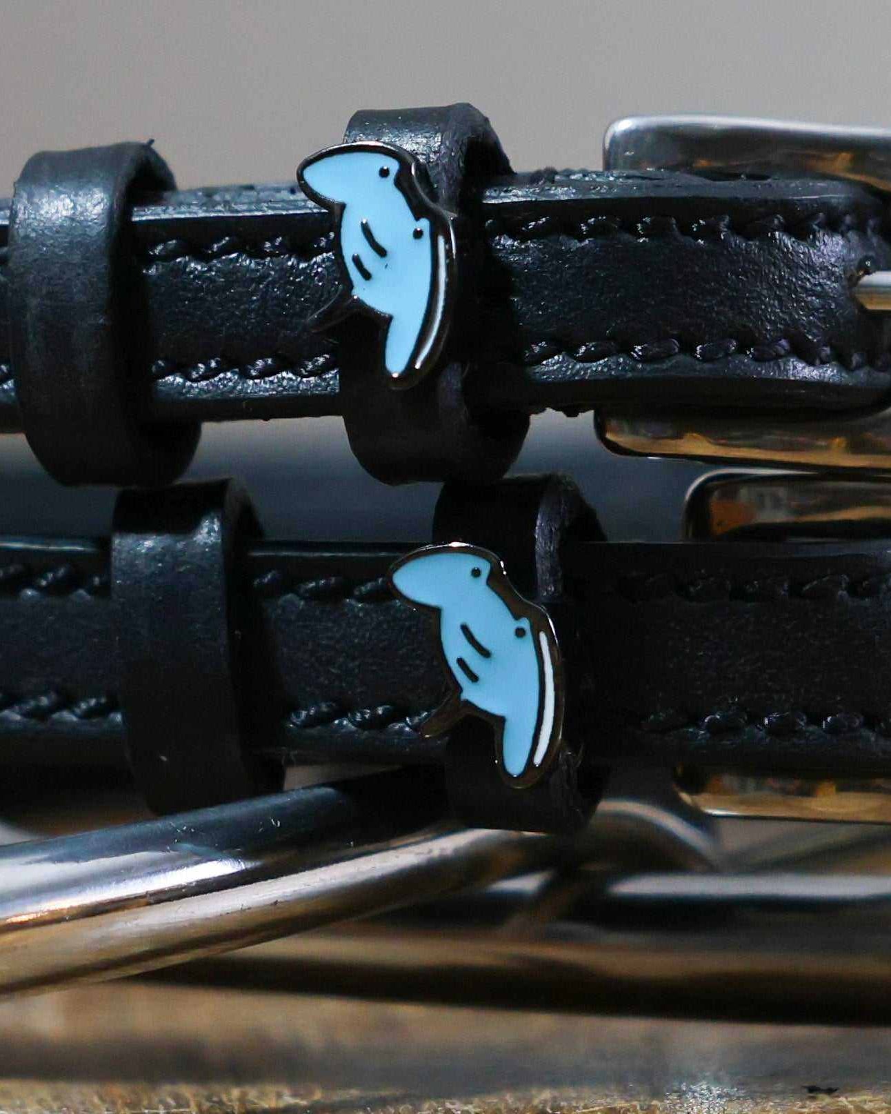 Close-up of blue enamel stingray charms on black leather ManeJane spur strap keepers