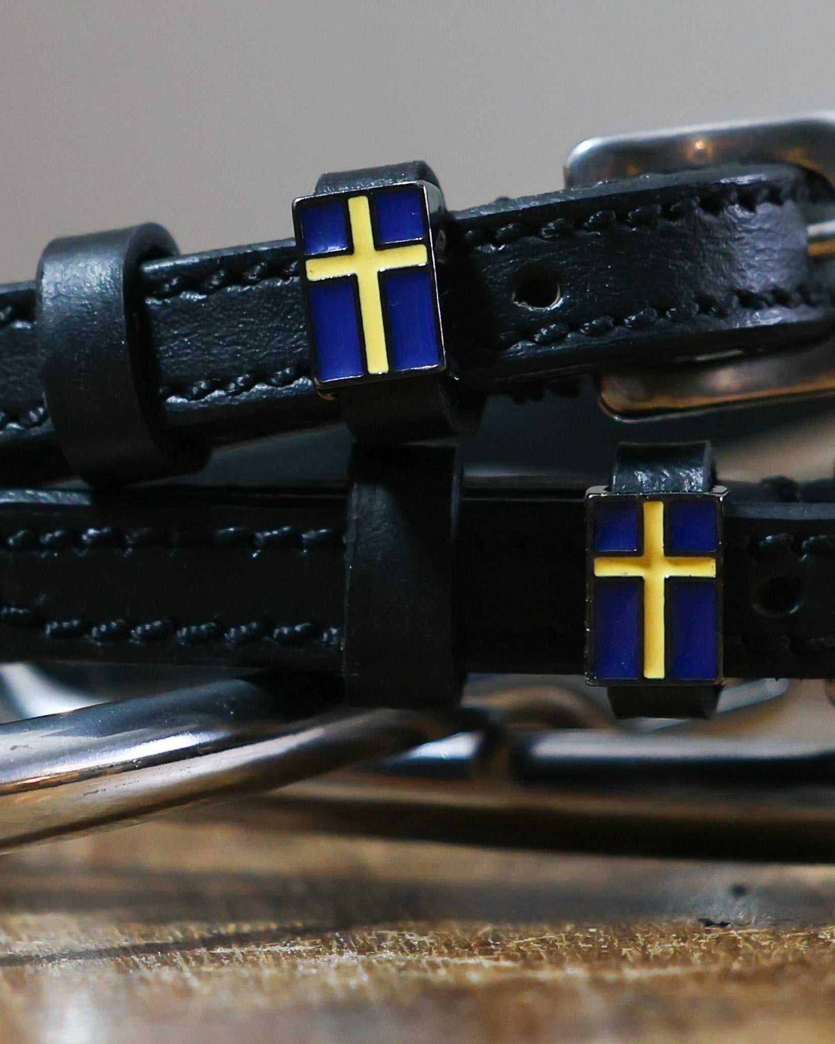Close-up of a blue-and-yellow Swedish flag charm on a black leather spur strap