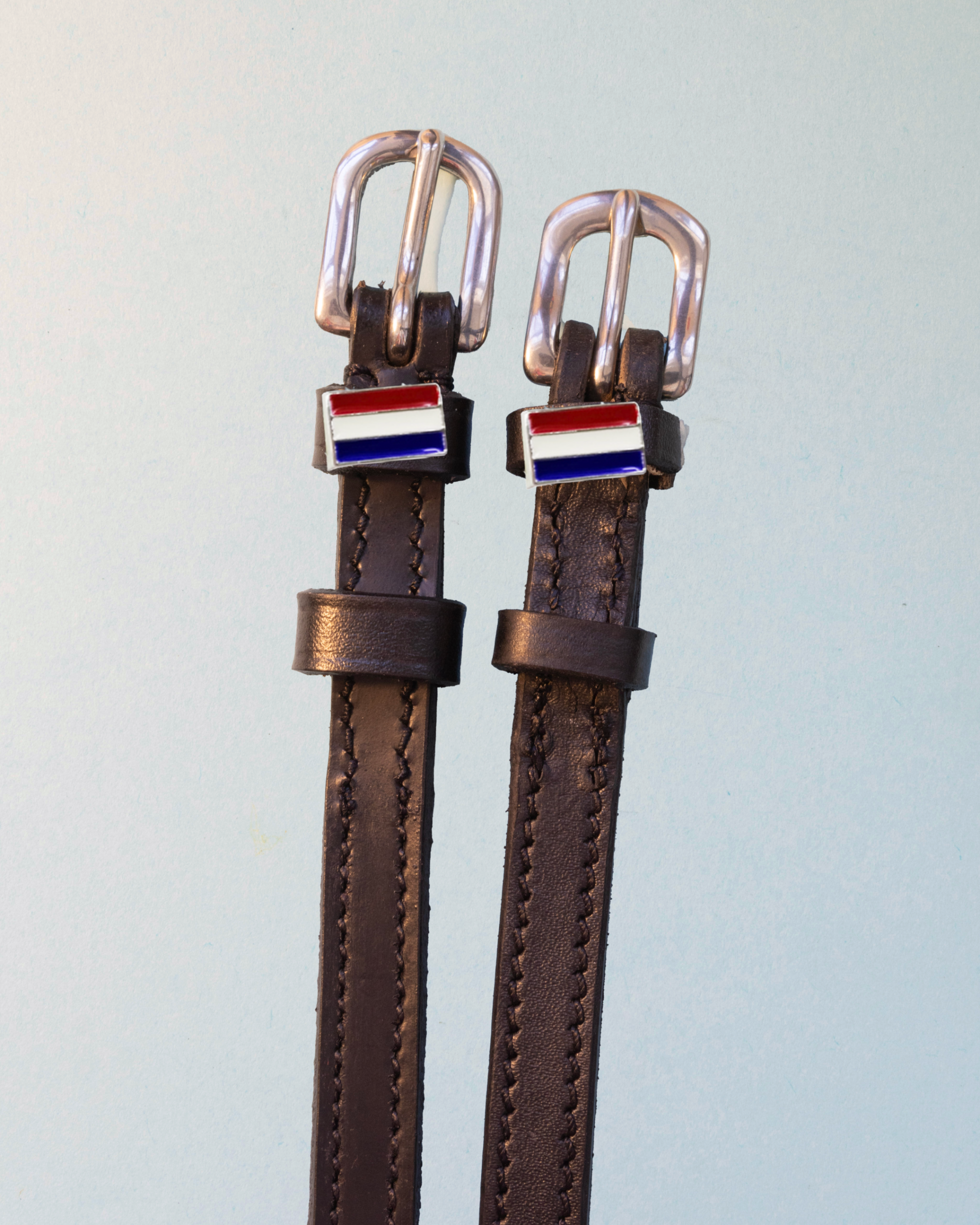 Brown leather ManeJane spur straps with red-white-blue tricolor flag charms and silver buckles