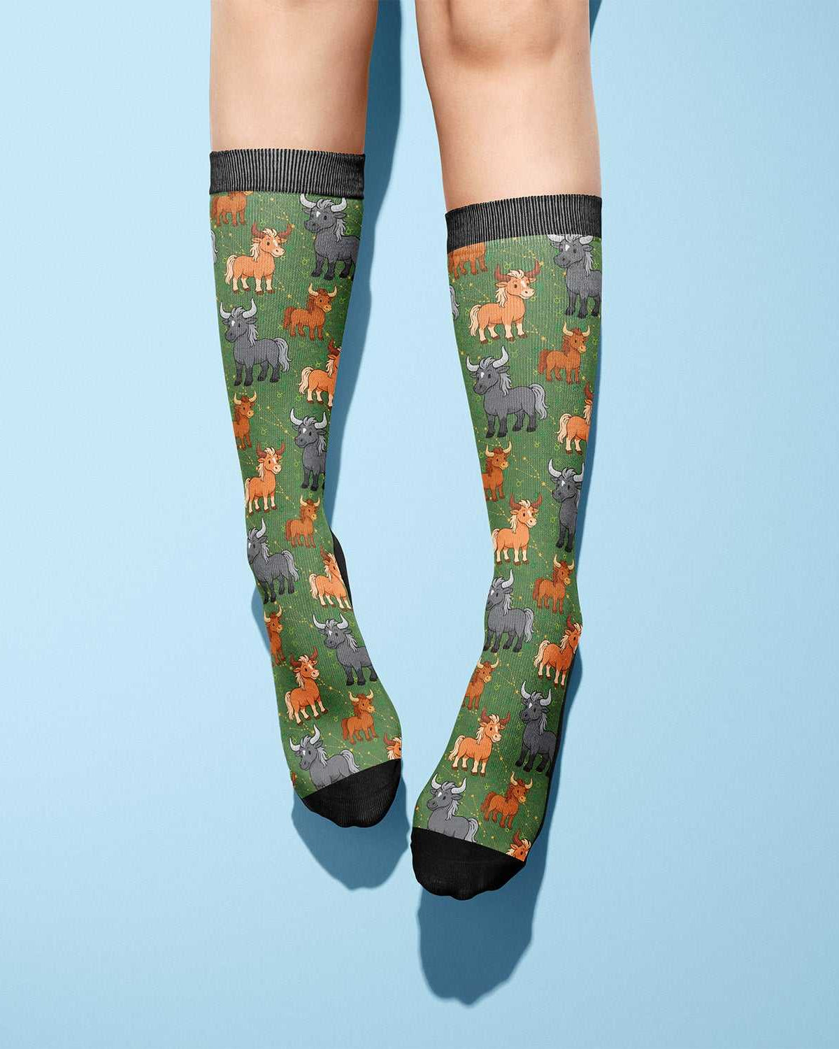 Taurus zodiac-themed boot socks with colorful bull patterns on green background