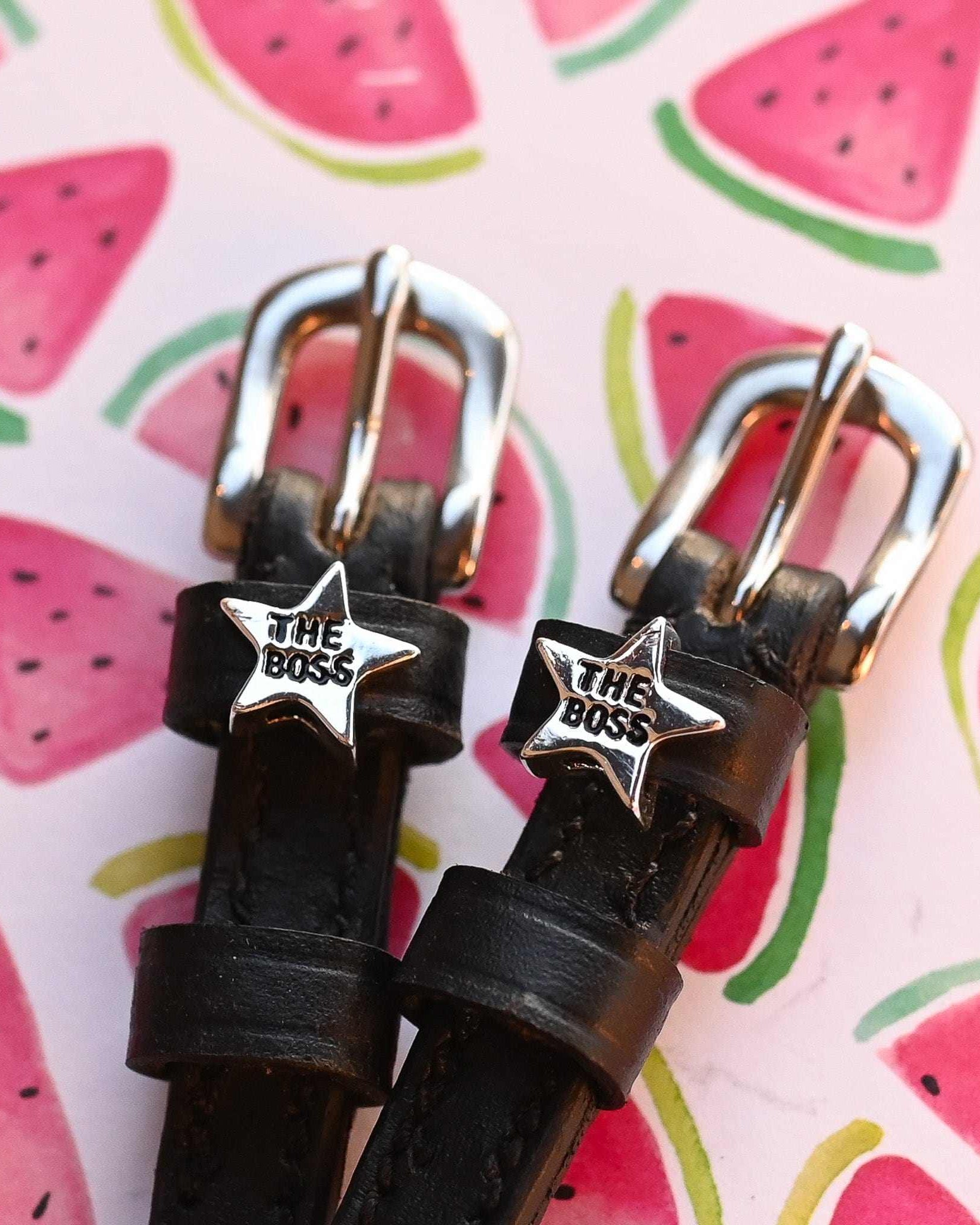 Close-up of 'The Boss' silver star charms on ManeJane spur straps over a watermelon print