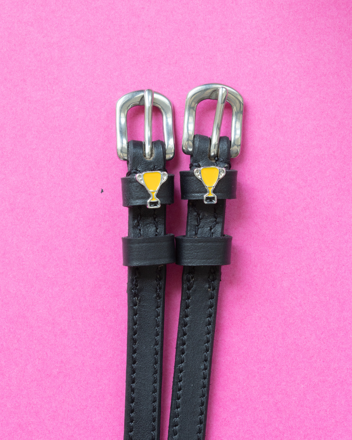Trophy ManeJane spur straps with the signature Trophy charm, shown on a pink background