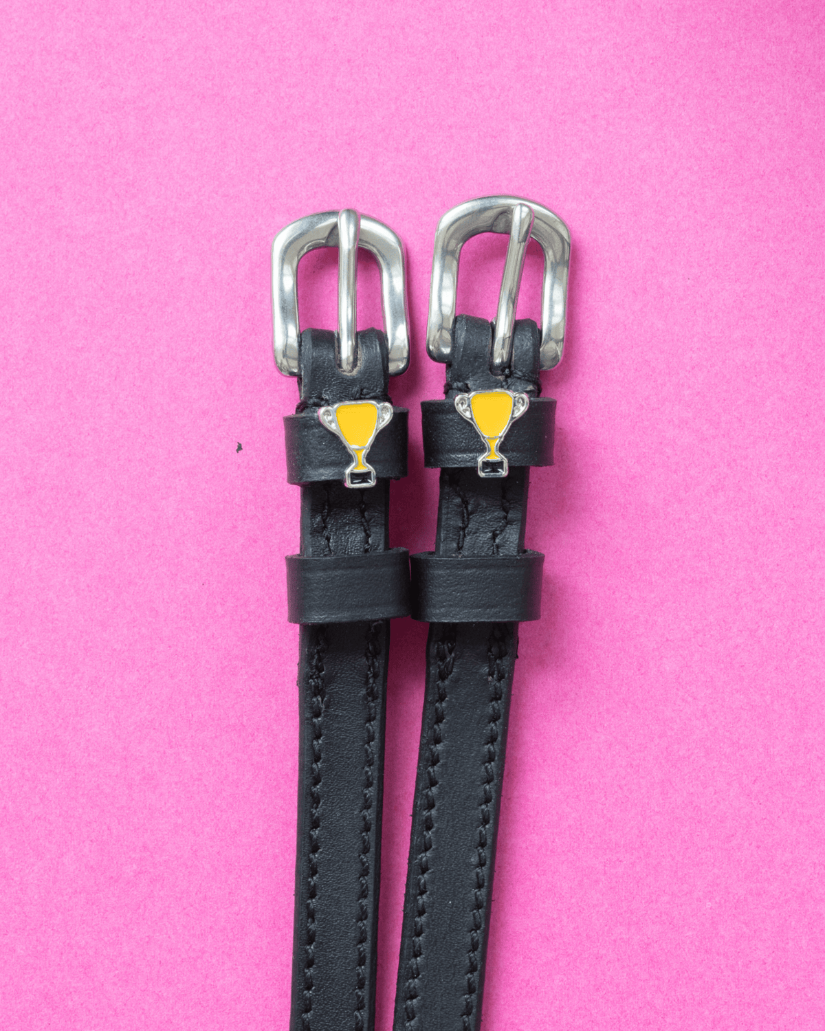 Trophy ManeJane spur straps with the signature Trophy charm, shown on a pink background