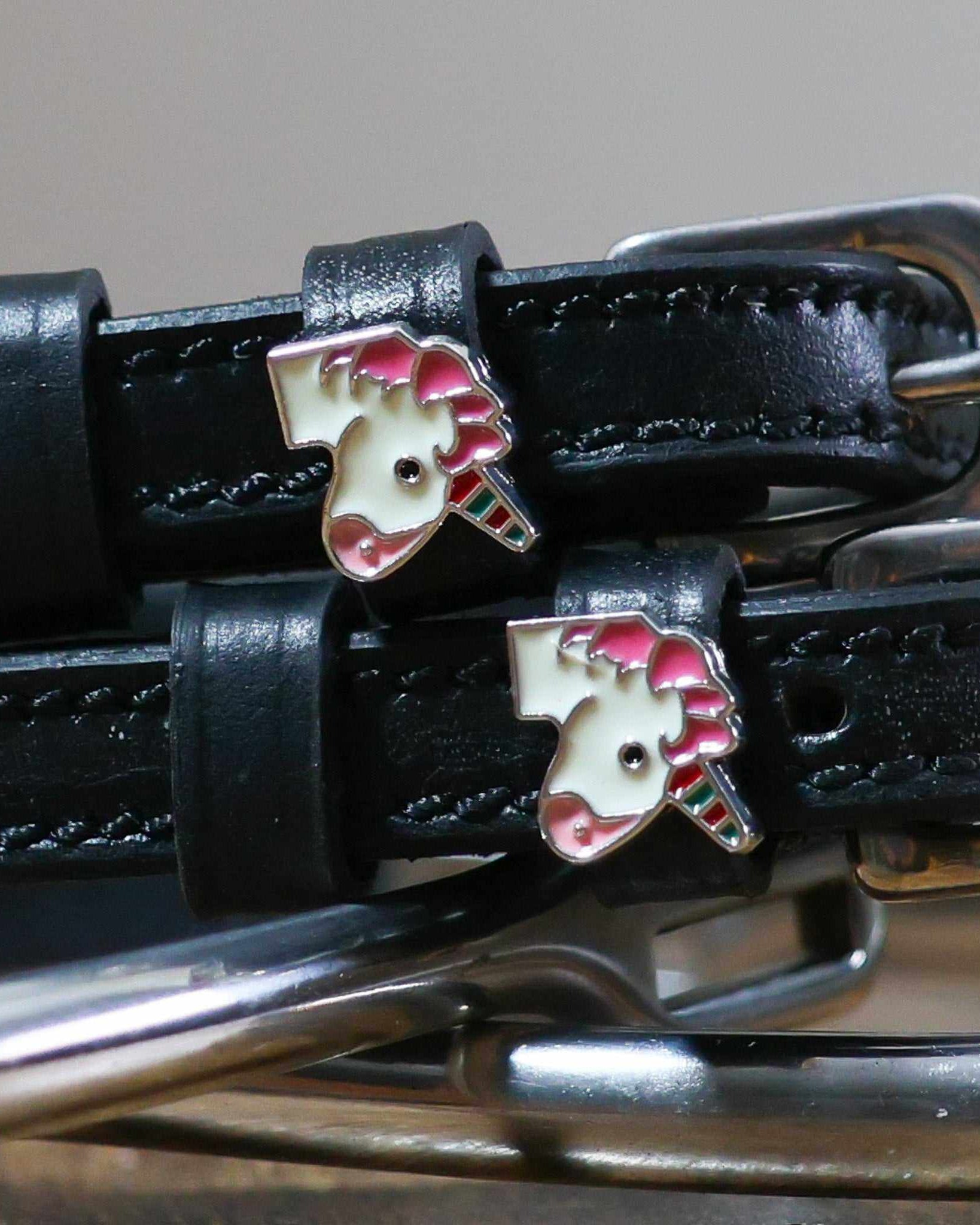 Close-up of enamel unicorn head charms on black leather ManeJane spur strap keepers
