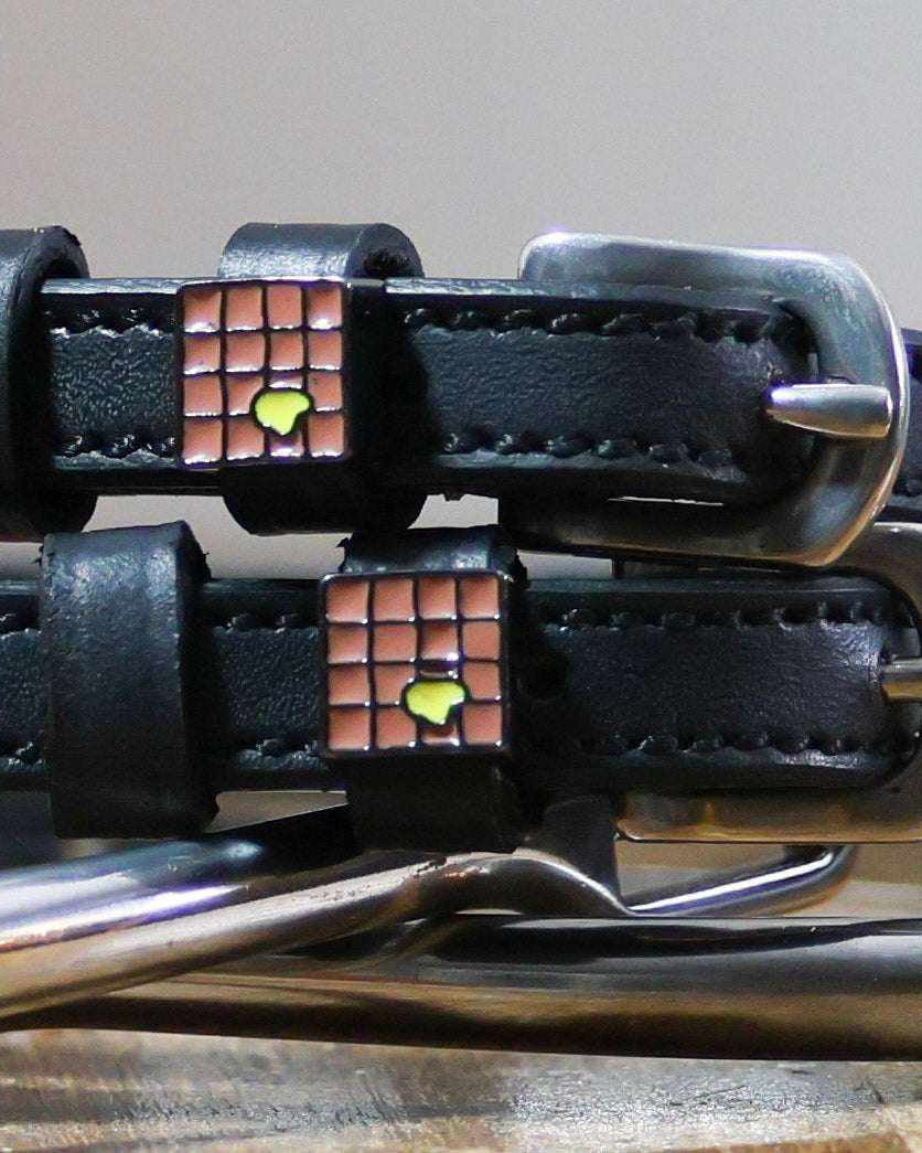 Close-up of enamel waffle charms with a pat of butter on black spur straps