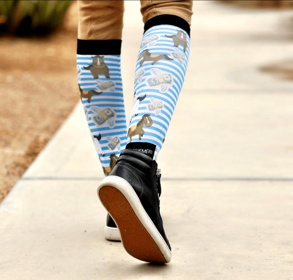 Equestrian wearing blue striped Cash Money Bundle socks with horses and money design walking on pavement