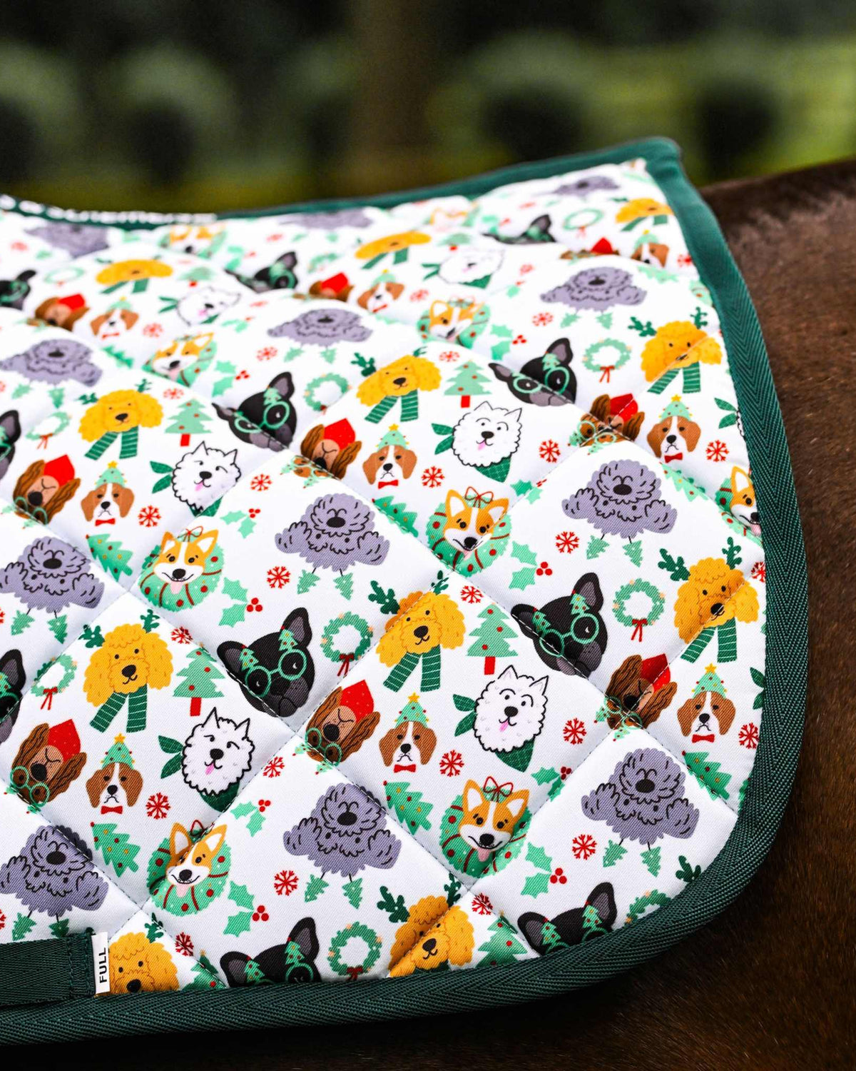 Deck the Paws Saddle Pad with playful dog pattern and green trim on horse saddle.