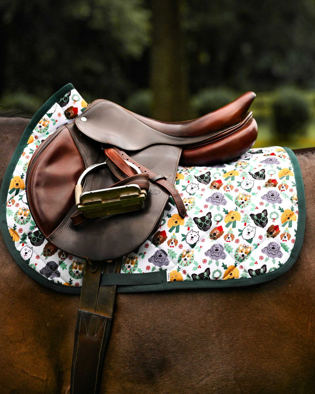 Deck the Paws Saddle Pad with playful paw print design under brown saddle on horse back