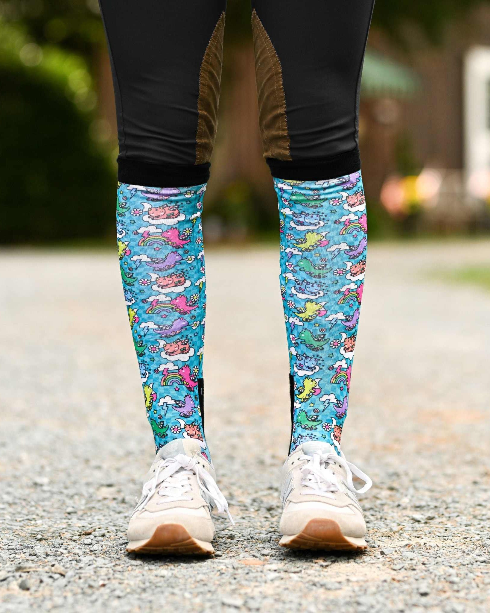 Colorful knee-high Dragon Dreams socks with fantasy design on a rider's legs outdoors