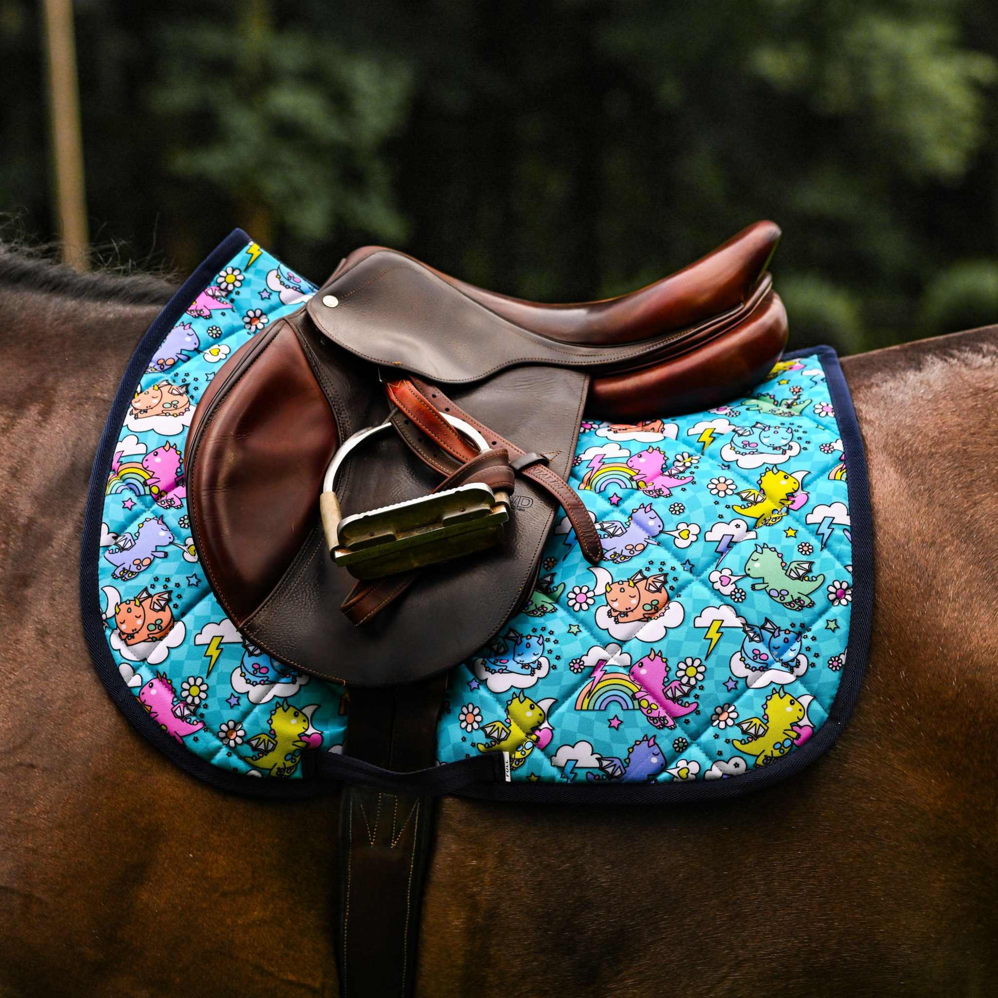 Colorful dragon-themed saddle pad with brown leather saddle and stirrups on horse back from Dragon Dreams Bundle