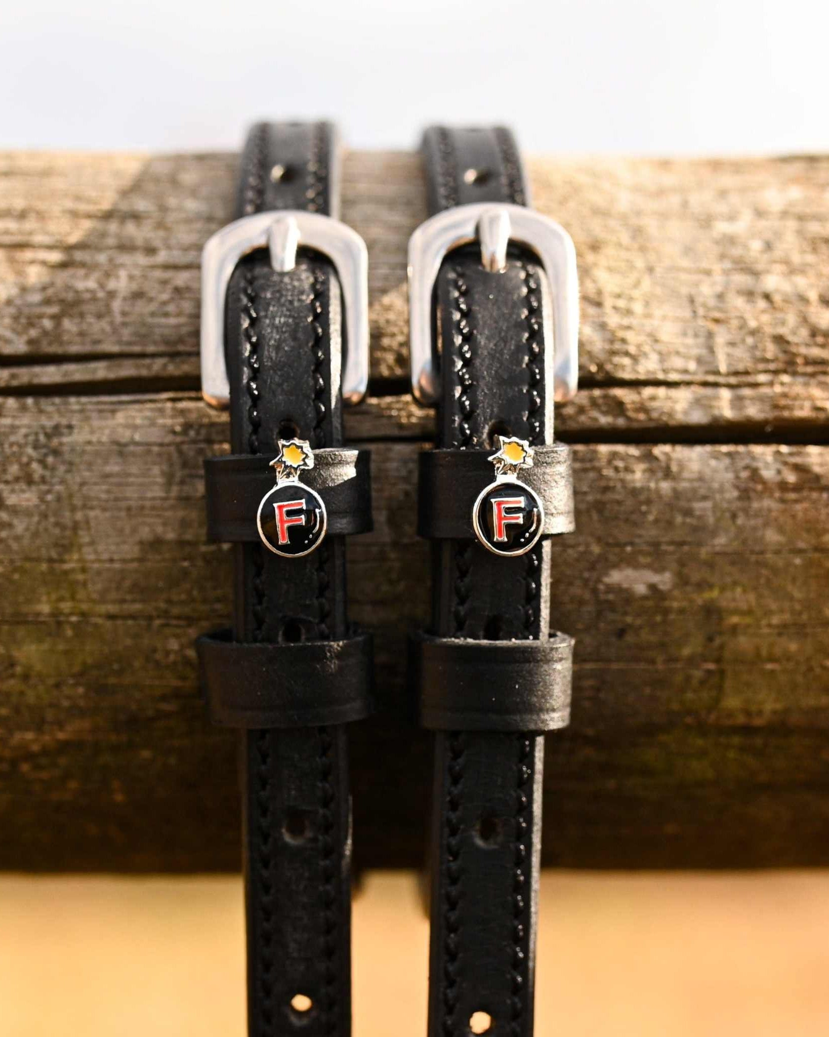 Black leather spur straps with silver buckles and F-Bomb charm from Ultimate F-Bomb Pack equestrian accessories.