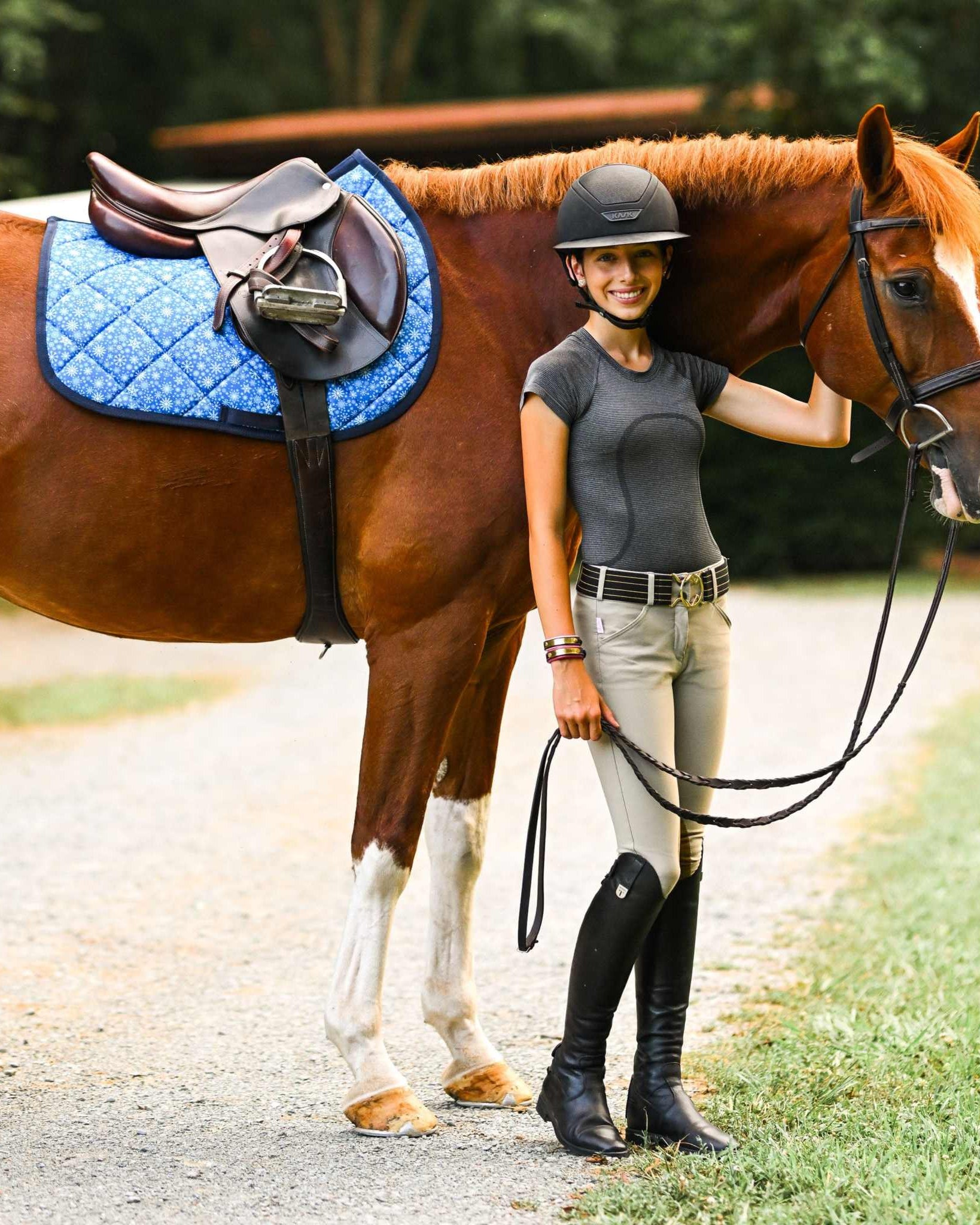 Flake It til You Make It blue quilted saddle pad on horse with rider standing beside outdoors