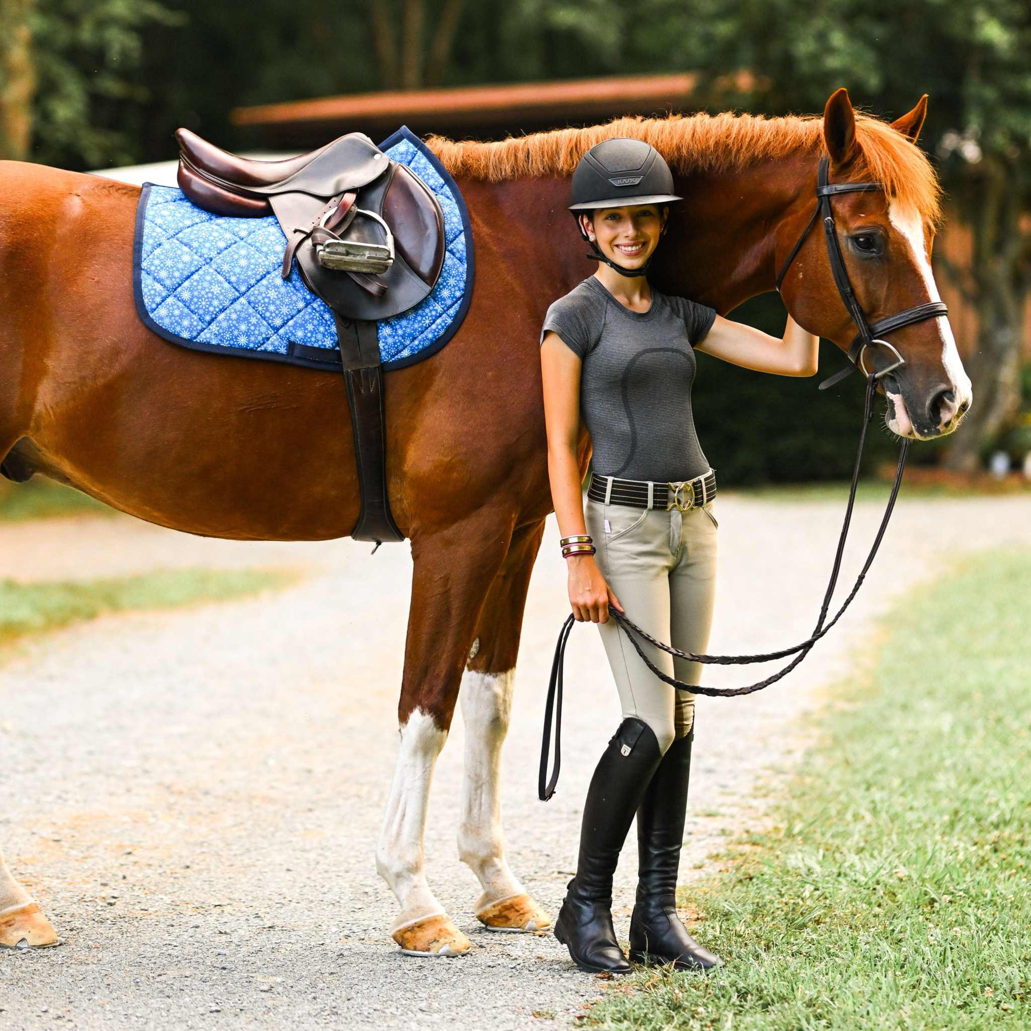 Flake It til You Make It blue quilted saddle pad on horse with rider standing beside outdoors