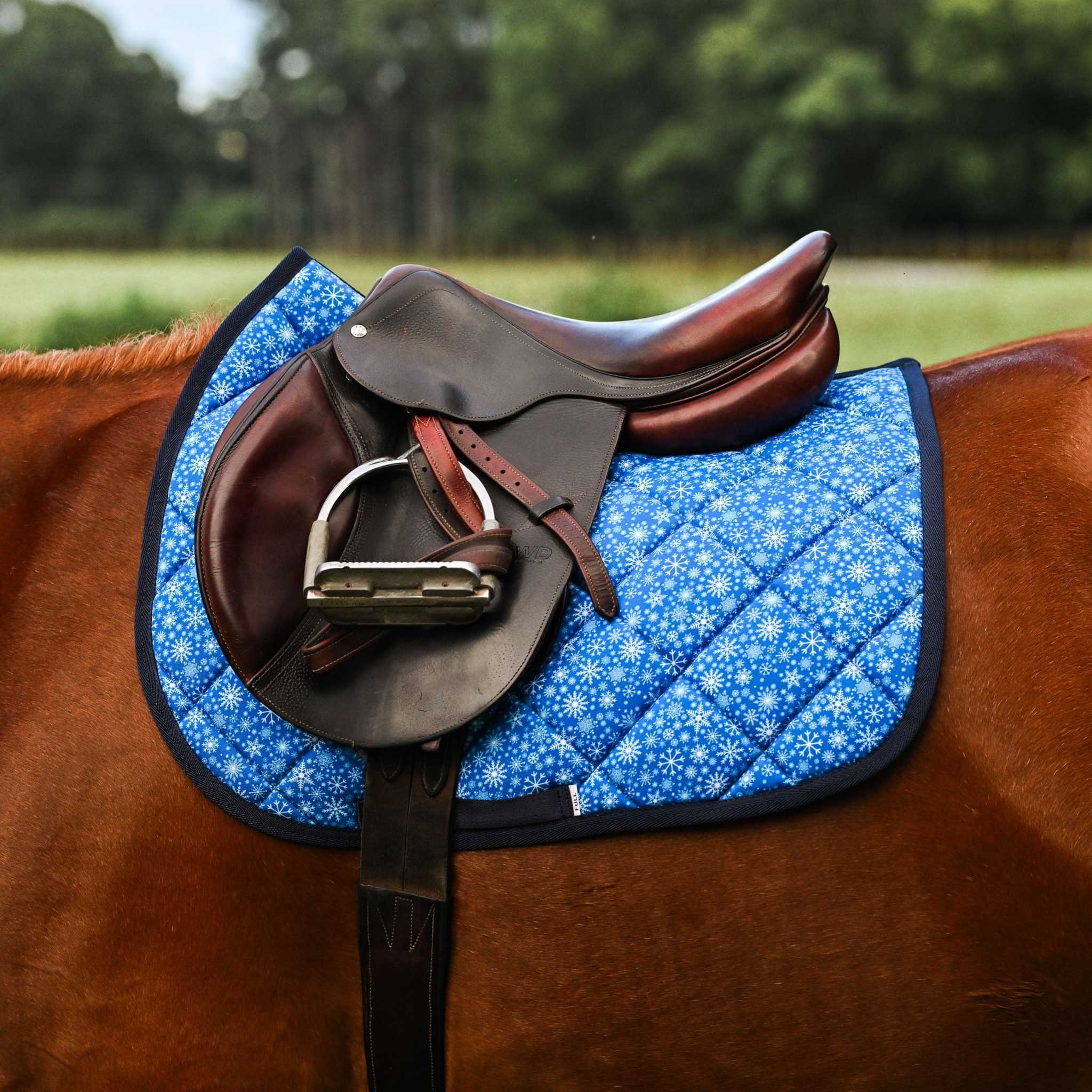 Blue Flake It til You Make It saddle pad with snowflake pattern under brown English saddle on horse
