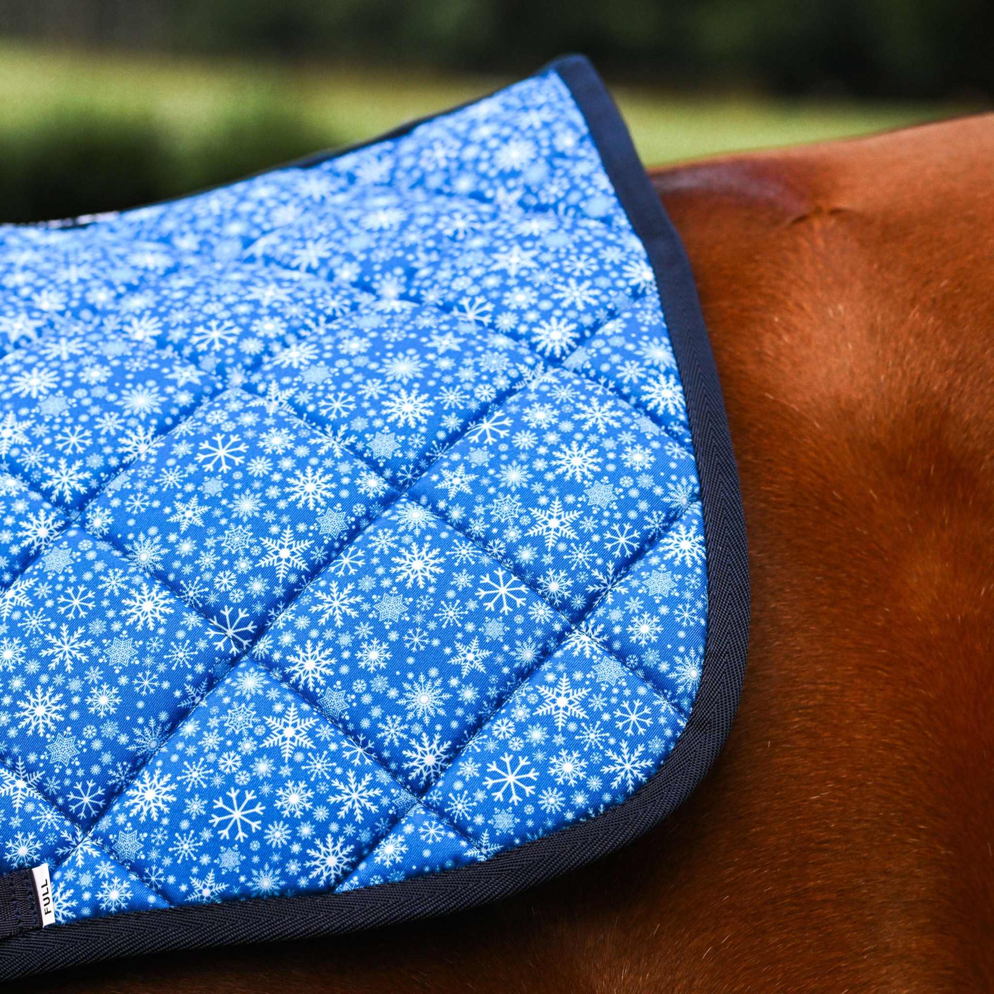 Blue Flake It til You Make It saddle pad with snowflake pattern on horse back