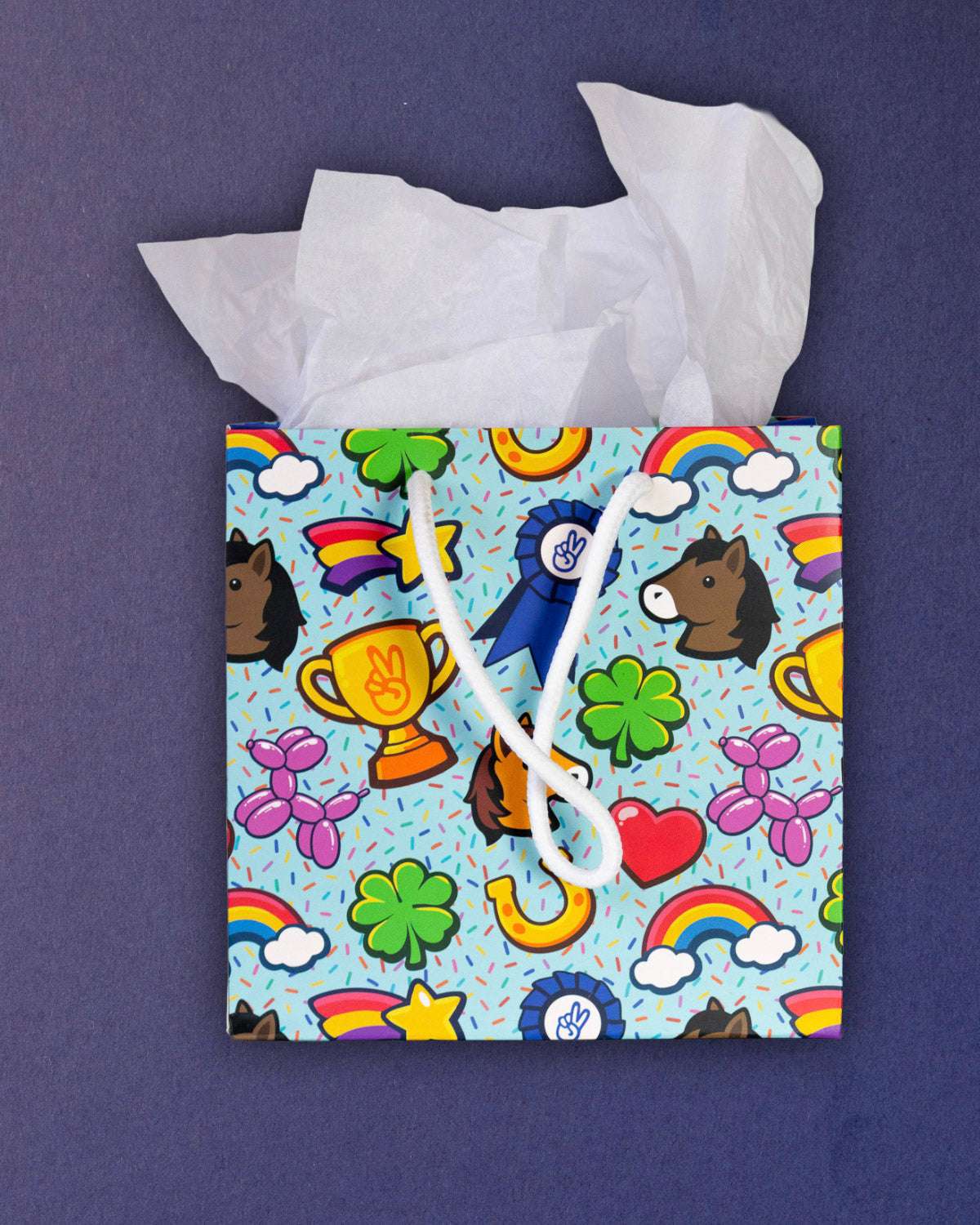 Full O' Luck small gift bag standing front-on, tissue paper above trophies, clovers and rainbows.