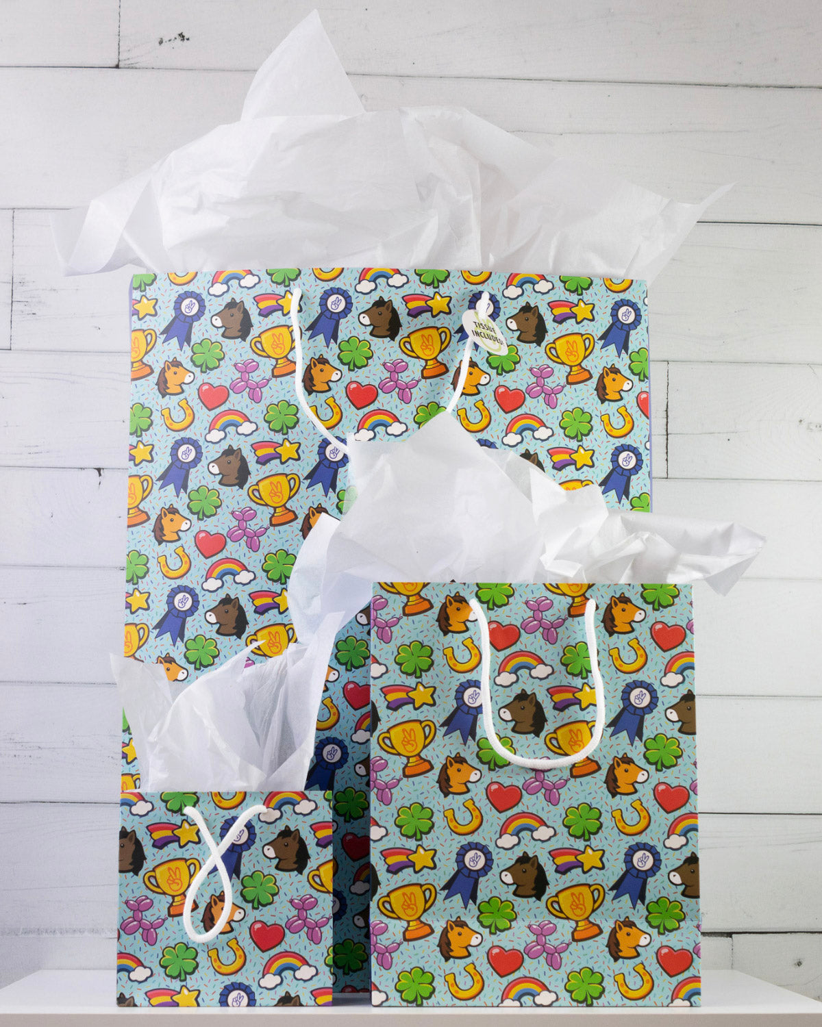 Full O' Luck gift bags in all three sizes on a white shelf, large behind with medium and small in front.