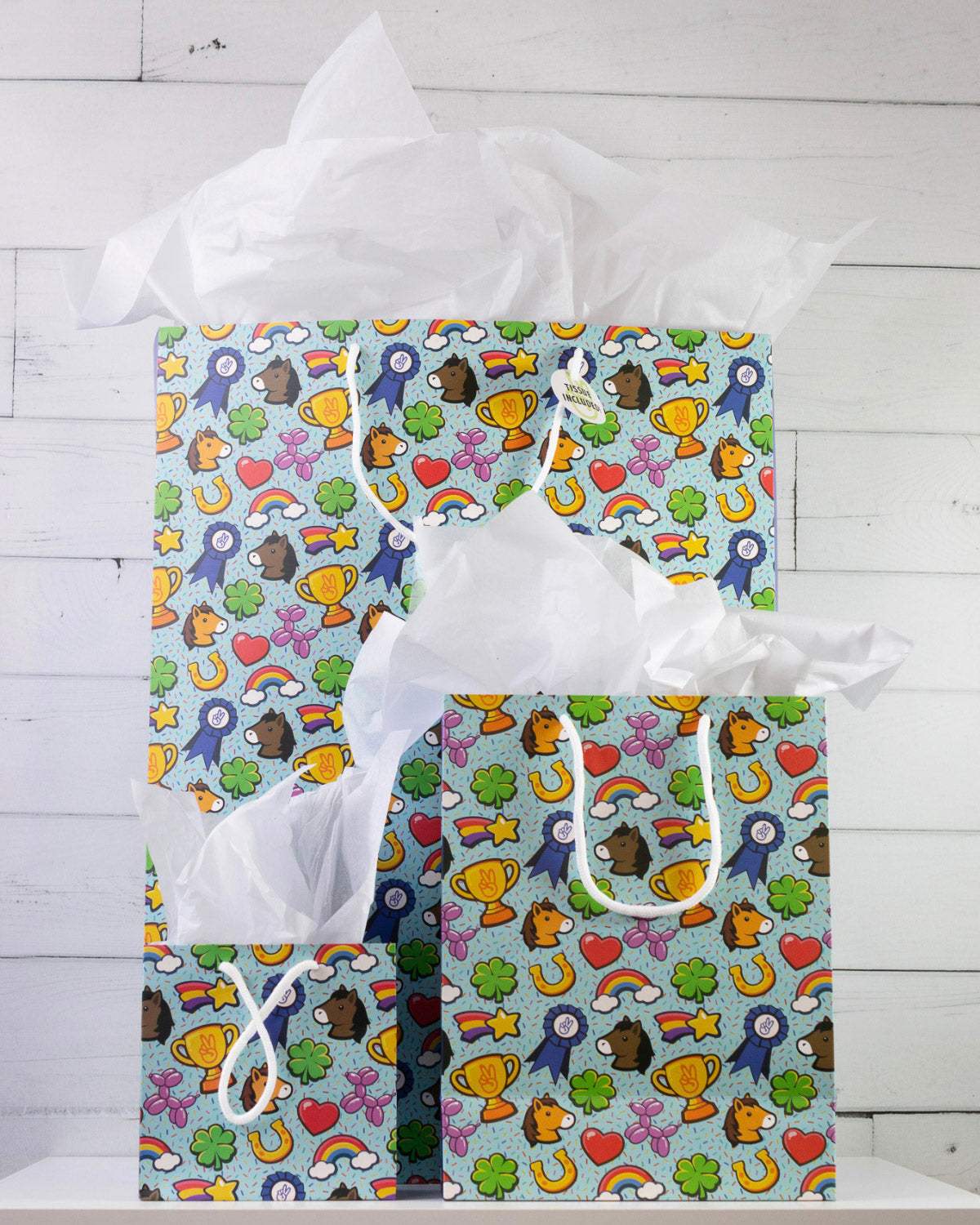 Full O' Luck gift bags in all three sizes on a white shelf, large behind with medium and small in front.