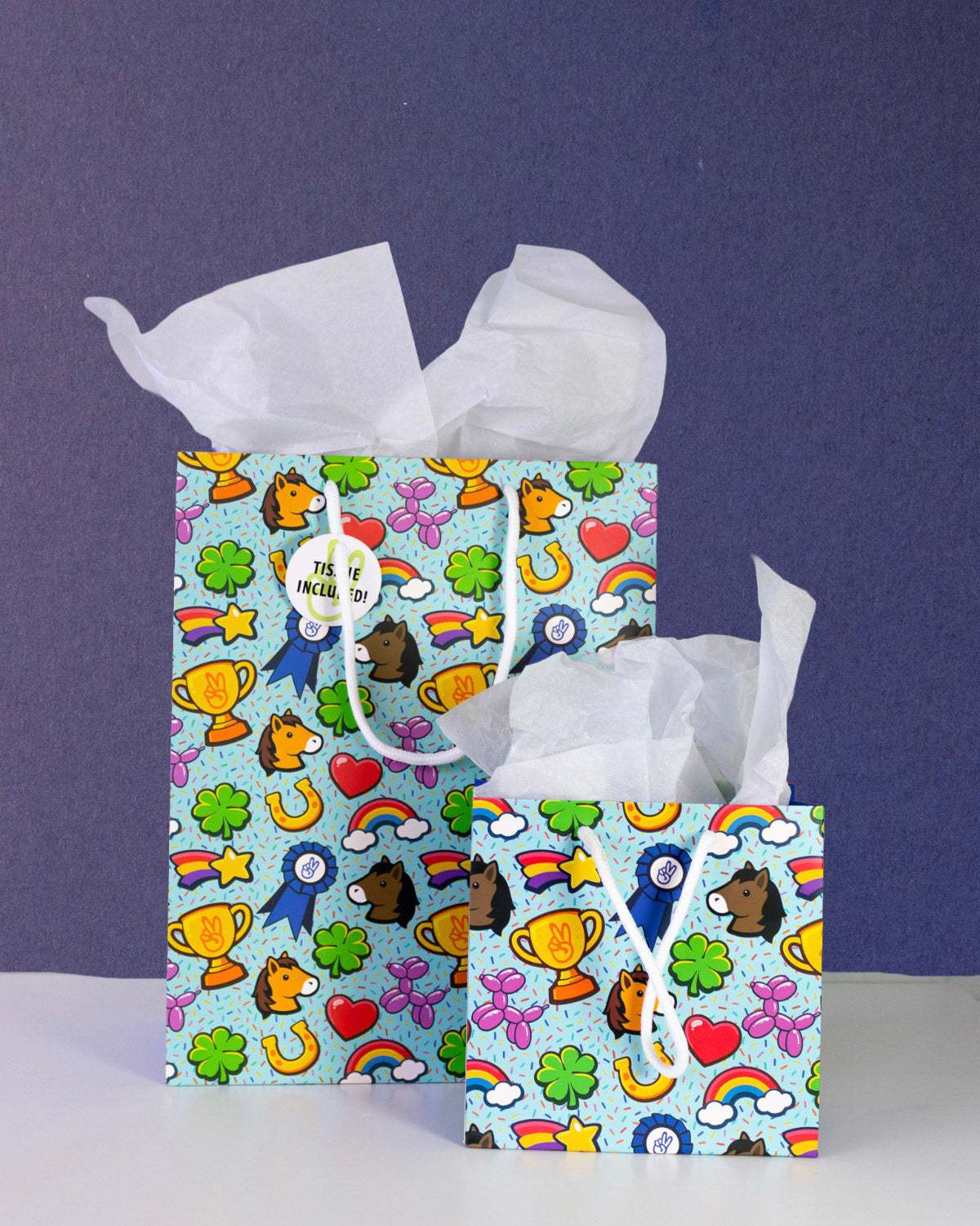Full O' Luck gift bags in medium and small together on navy, both stuffed with white tissue paper.