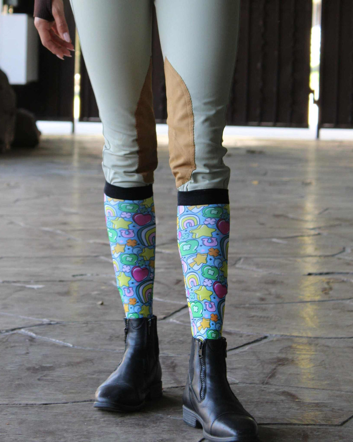 Youth equestrian wearing colorful Lucky Equestrian Bundle socks with riding boots and beige riding pants