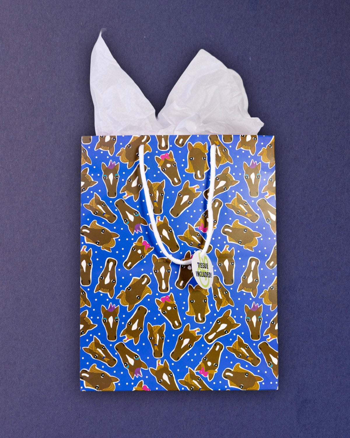 Hairy Styles medium gift bag front-on against navy, Tissue Included tag hanging from the rope handle.