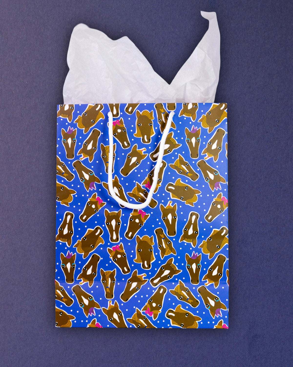 Hairy Styles medium gift bag flat from above, blue panel of pony faces with tissue paper fanned out.