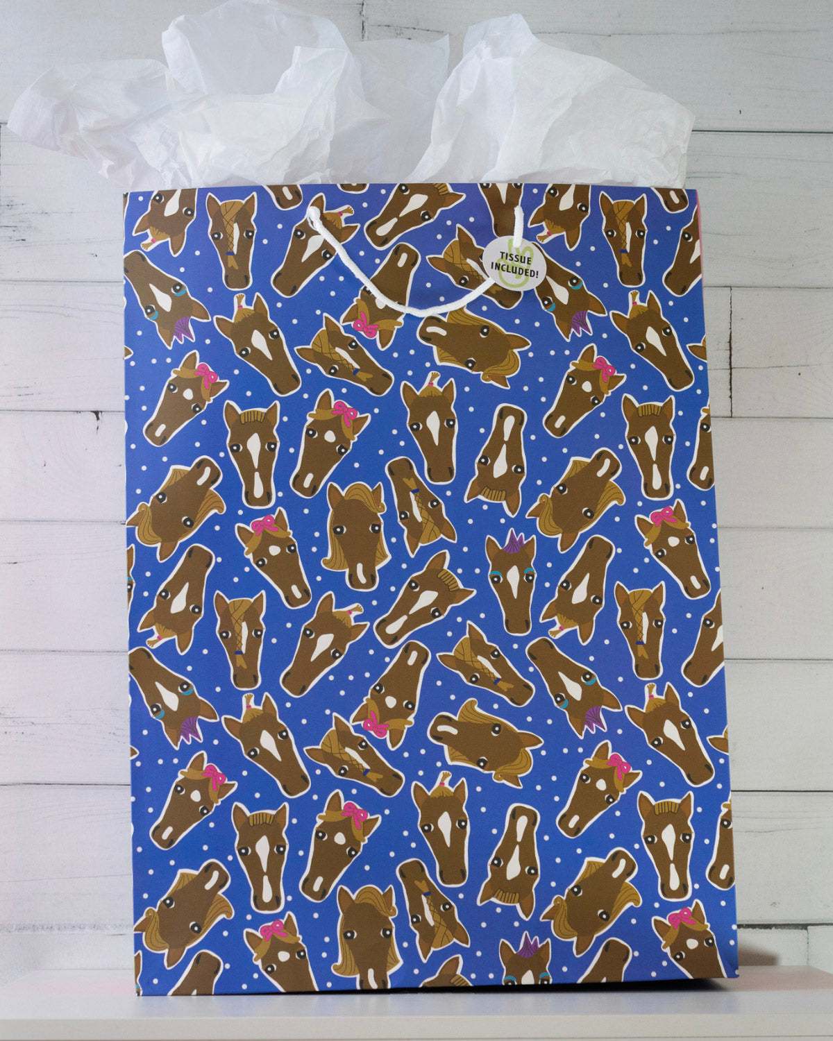 Hairy Styles large gift bag on a white shelf, royal blue panel of horse heads in braids, bows and ponytails.