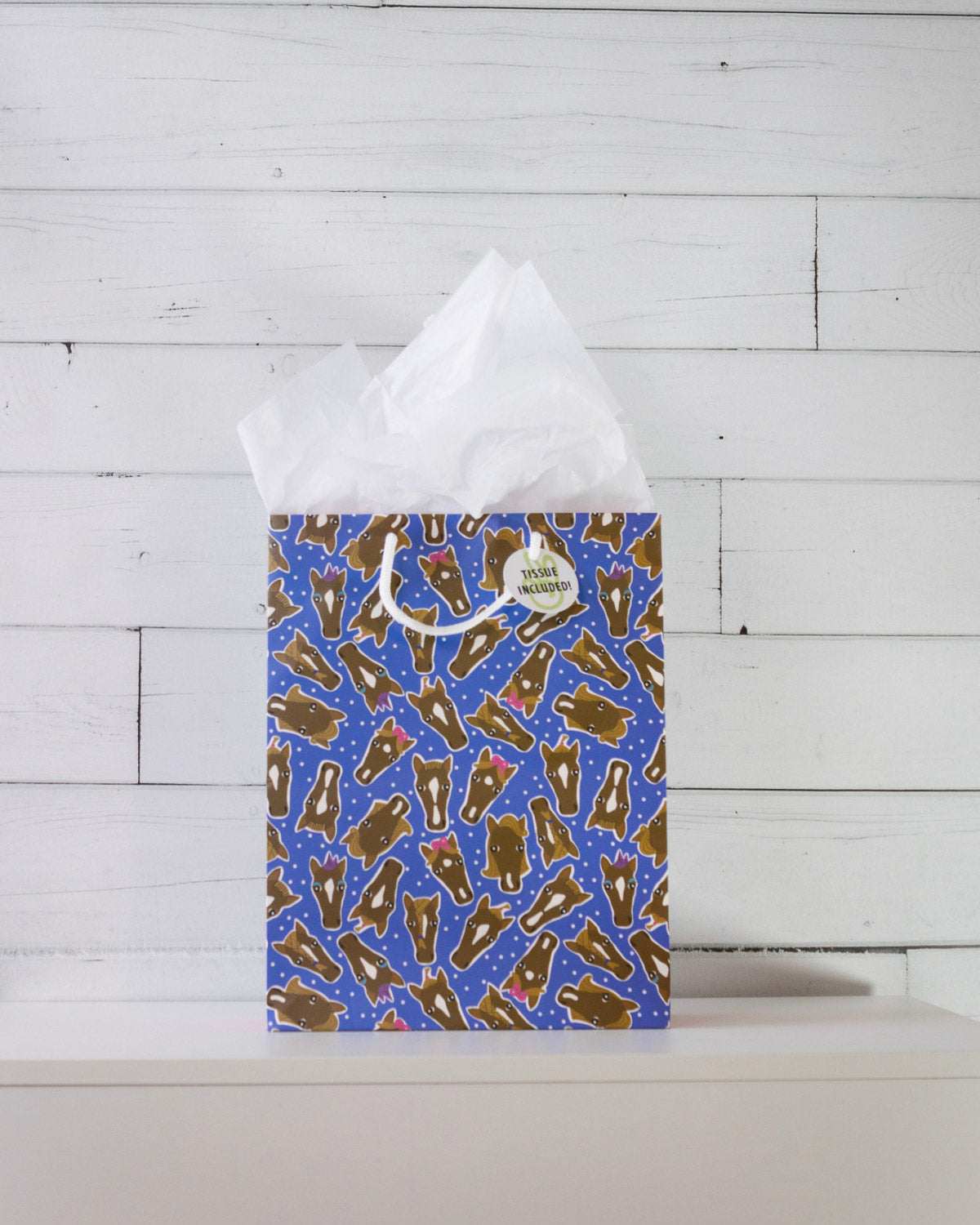 Hairy Styles medium gift bag on a white shelf, blue print of horse heads with different manes and bows.