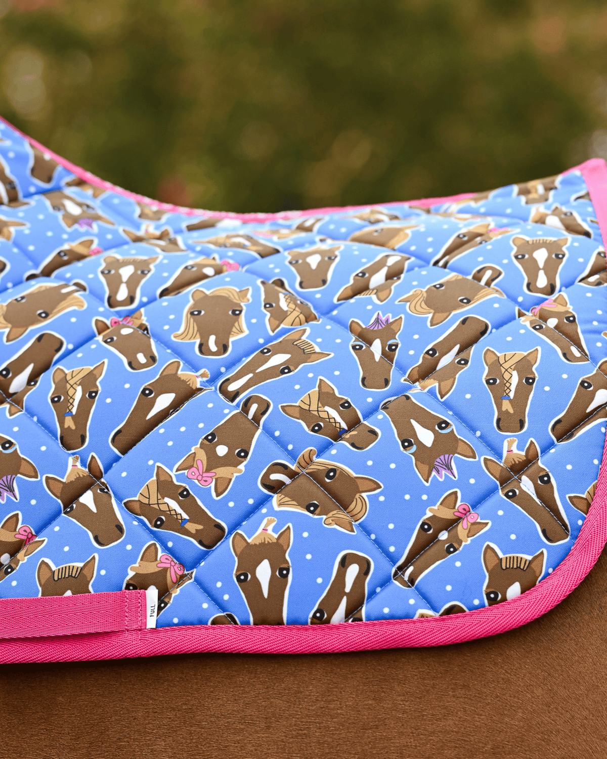 Close view of the Hairy Styles print — braided horse heads and white dots on blue, edged in hot pink