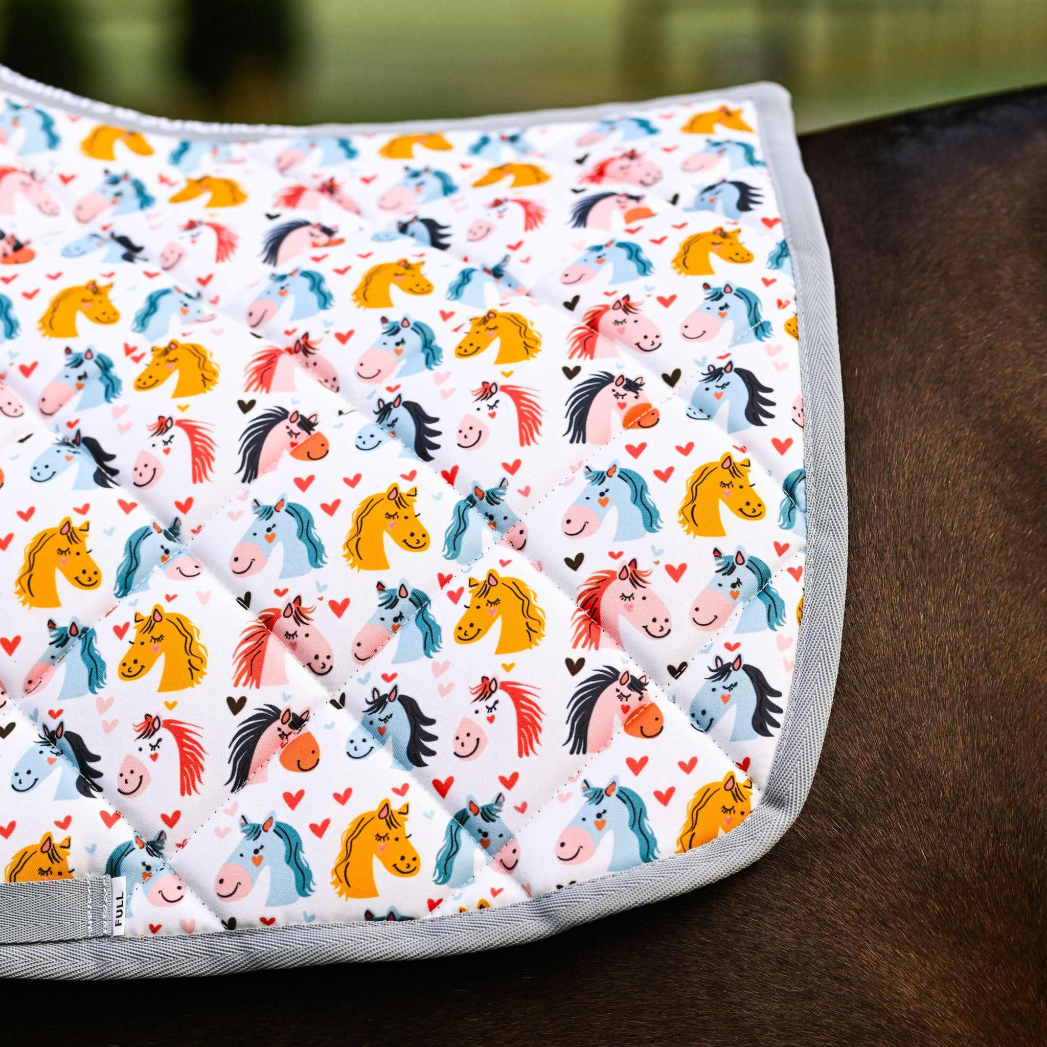 Just Horsing Around youth bundle saddle pad with colorful horse illustrations and hearts on a horse's back