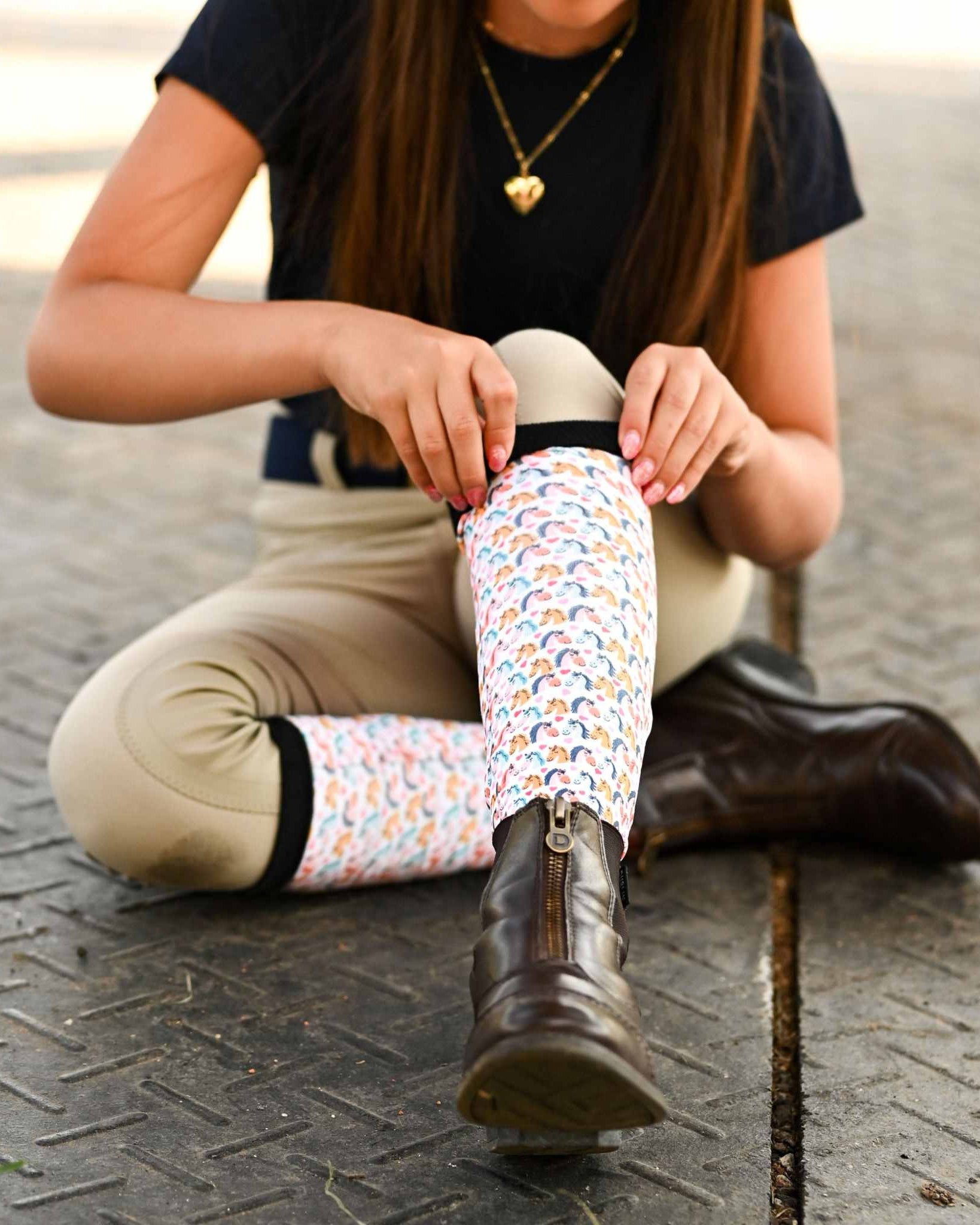 Youth wearing Just Horsing Around socks and brown riding boots sitting on pavement