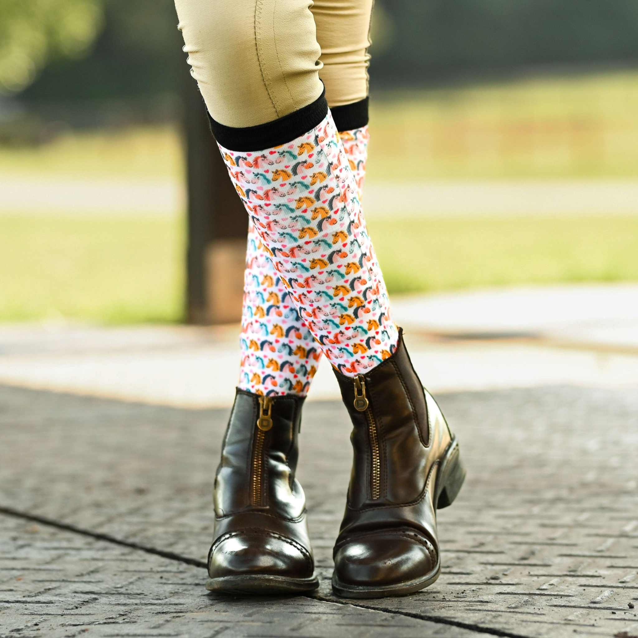 Just Horsing Around youth socks with colorful horse pattern worn with brown riding boots outdoors