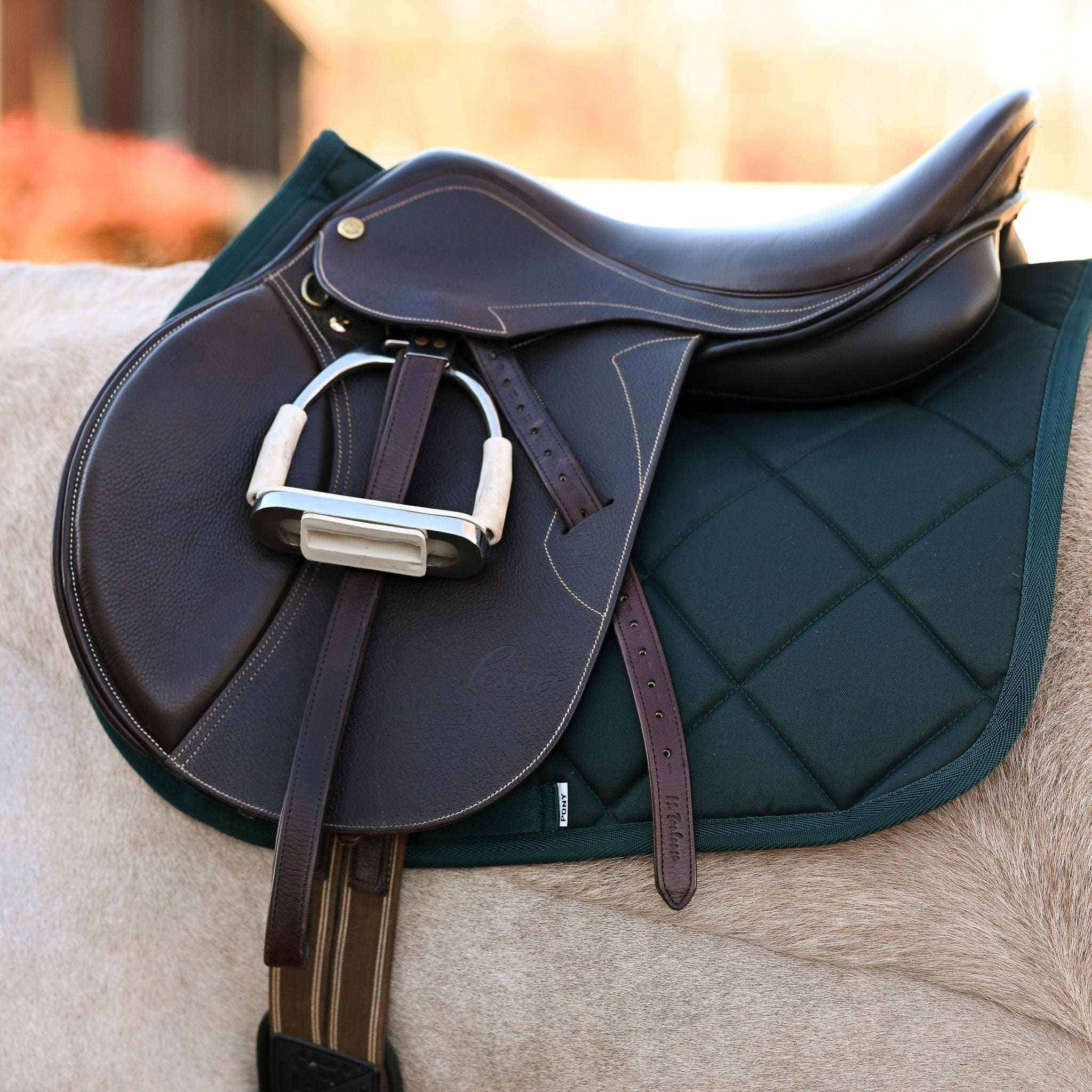 Hunter green saddle pad under brown equestrian saddle on horse back