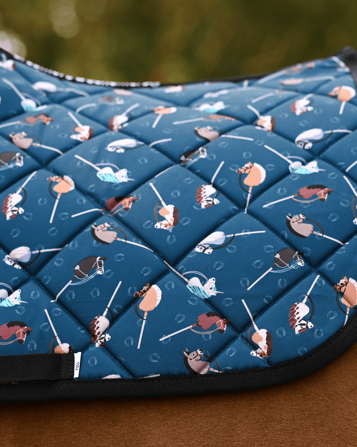 Detail of the It's Not a Hobby quilting: stick hobby horses and horseshoes on teal with black binding