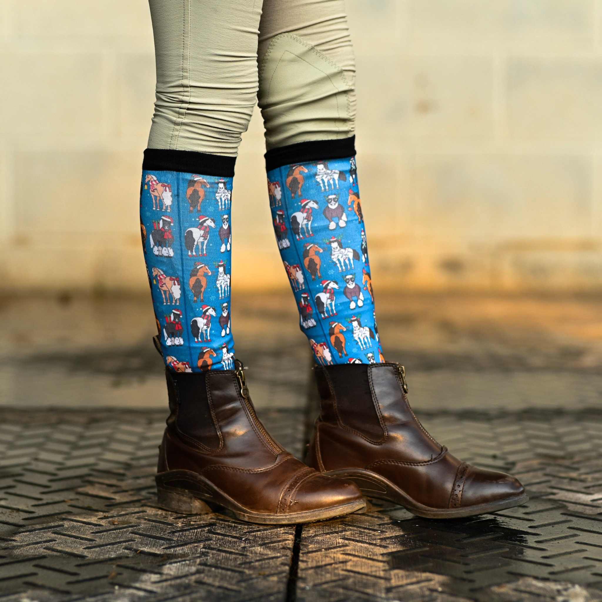 Youth riding boot socks with colorful horse patterns and black tops worn with brown riding boots