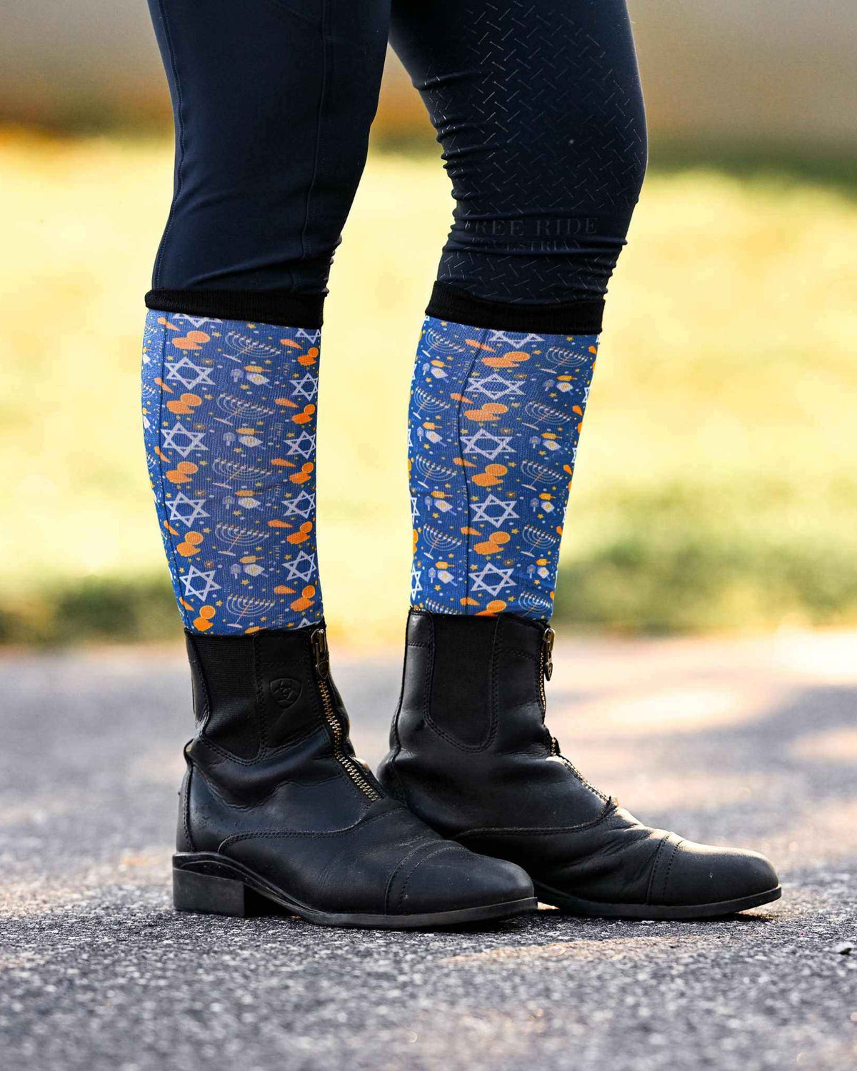 Keep Calm & Dreidel On holiday-themed riding socks with Star of David and dreidel patterns worn with black riding boots