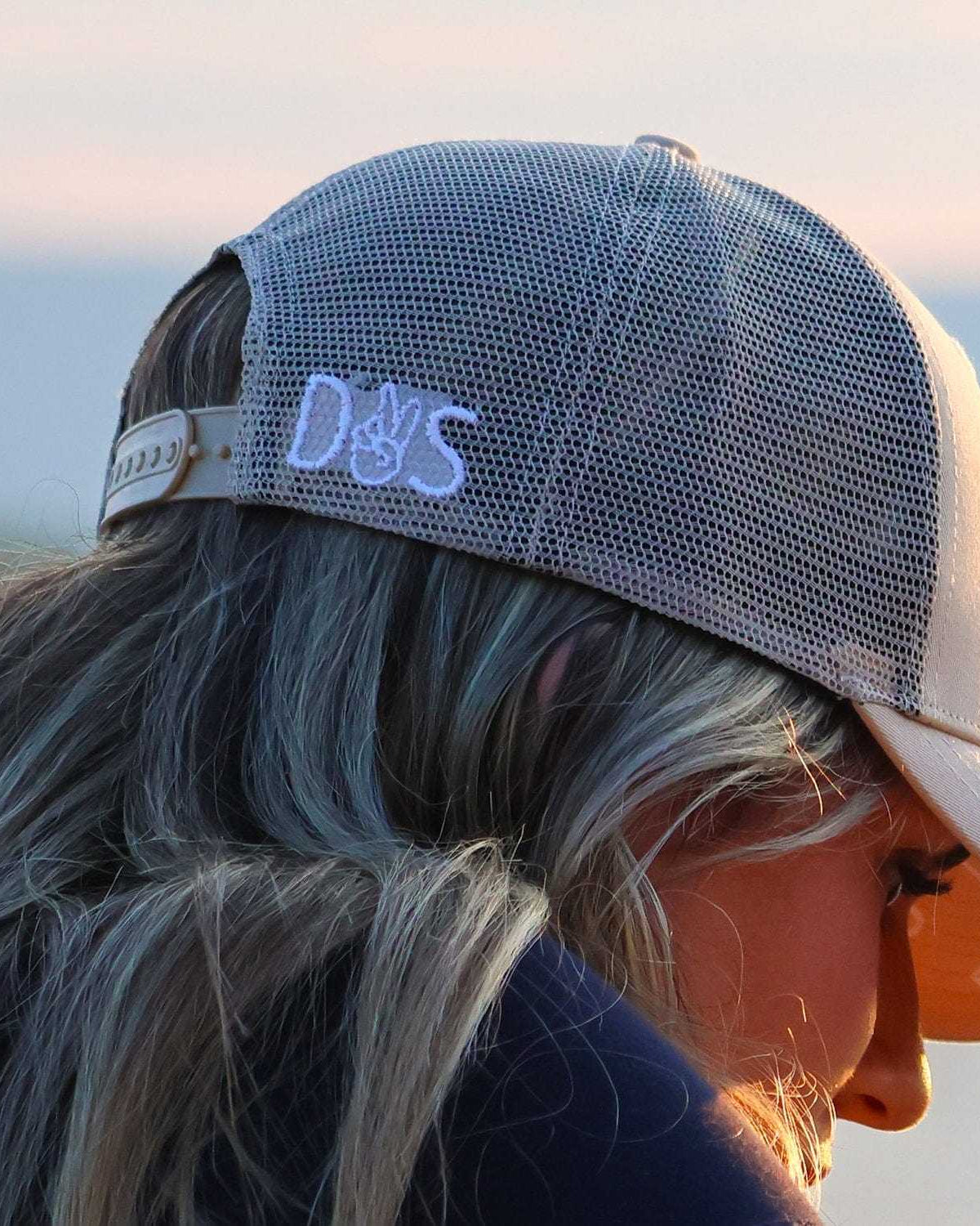 Woman wearing a gray breathable Muck This Equestrian Bundle trucker hat outdoors