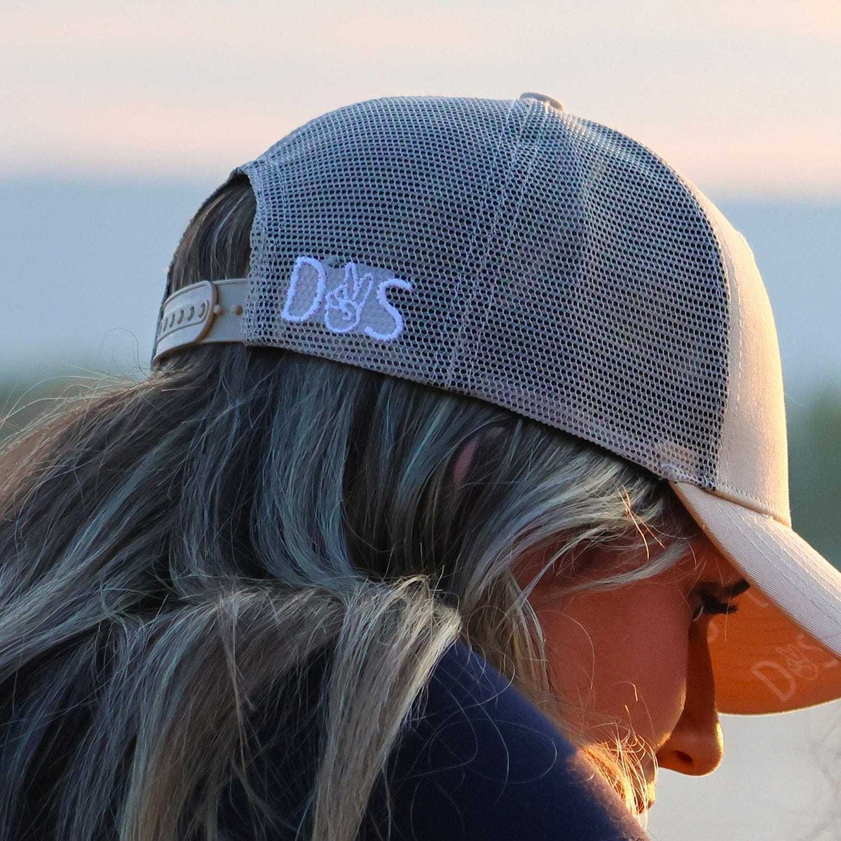 Woman wearing a gray breathable Muck This Equestrian Bundle trucker hat outdoors