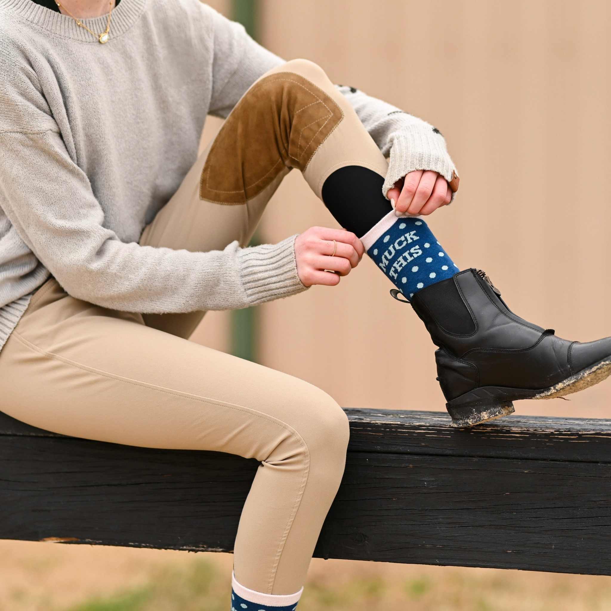 Person wearing Muck This Equestrian Bundle socks with tan riding pants and black boots outdoors