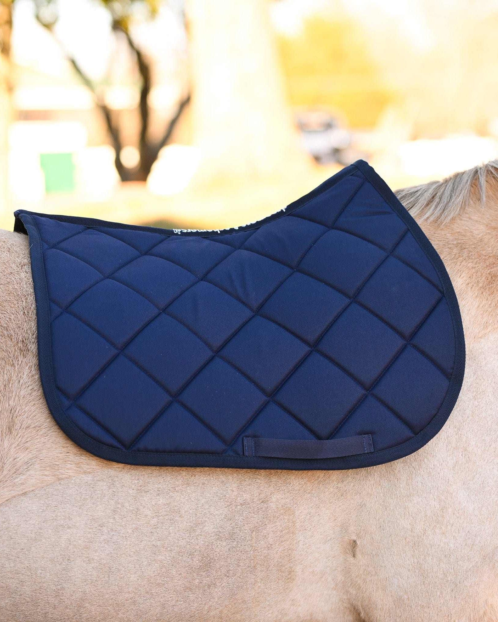 Navy blue quilted saddle pad on horse back from Blue Bundle equestrian set