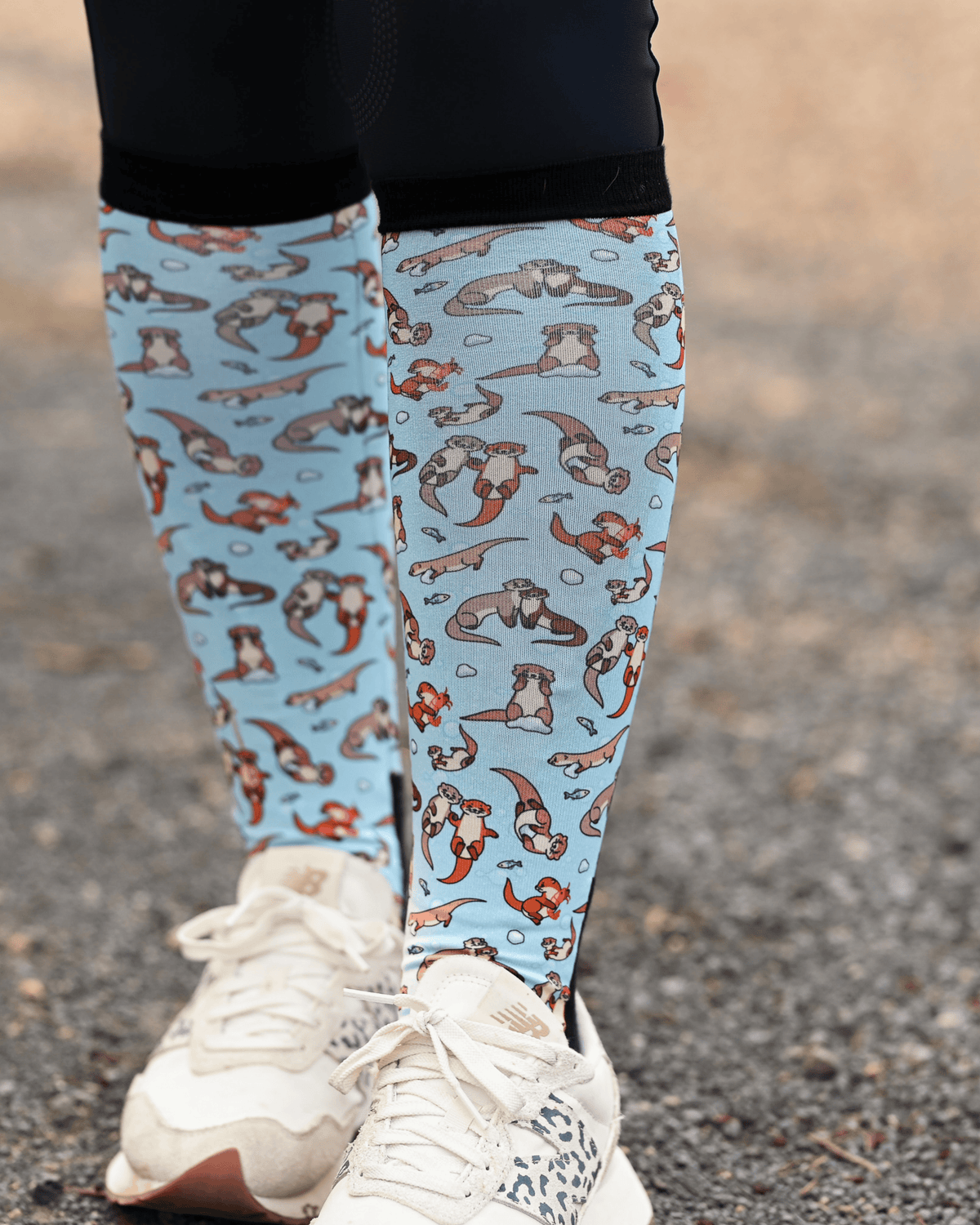 Otter-ly Adorable riding boot socks styled over breeches, pale blue with otters floating and holding hands