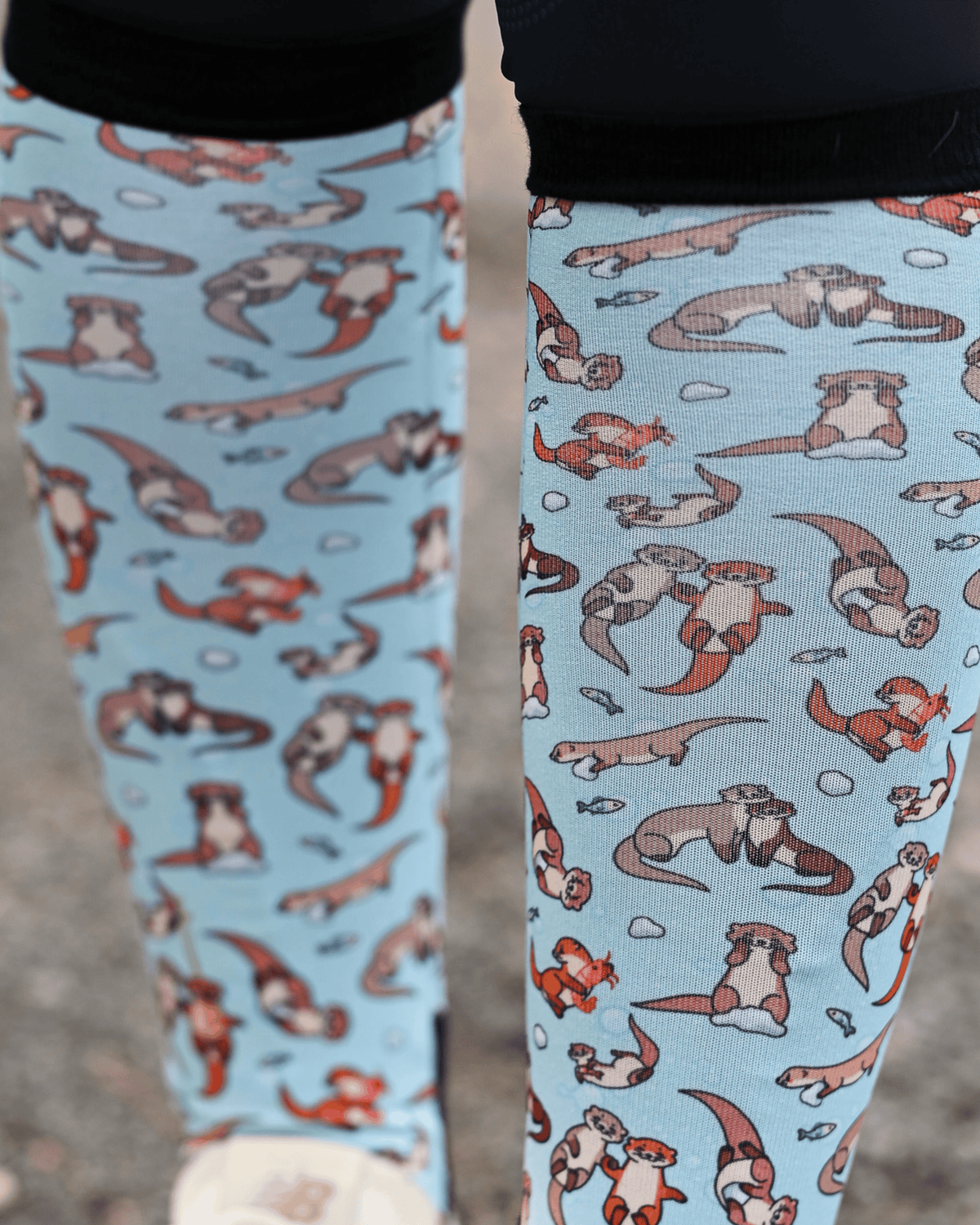 Close crop of the Otter-ly Adorable boot sock print, otters floating and holding hands on pale blue