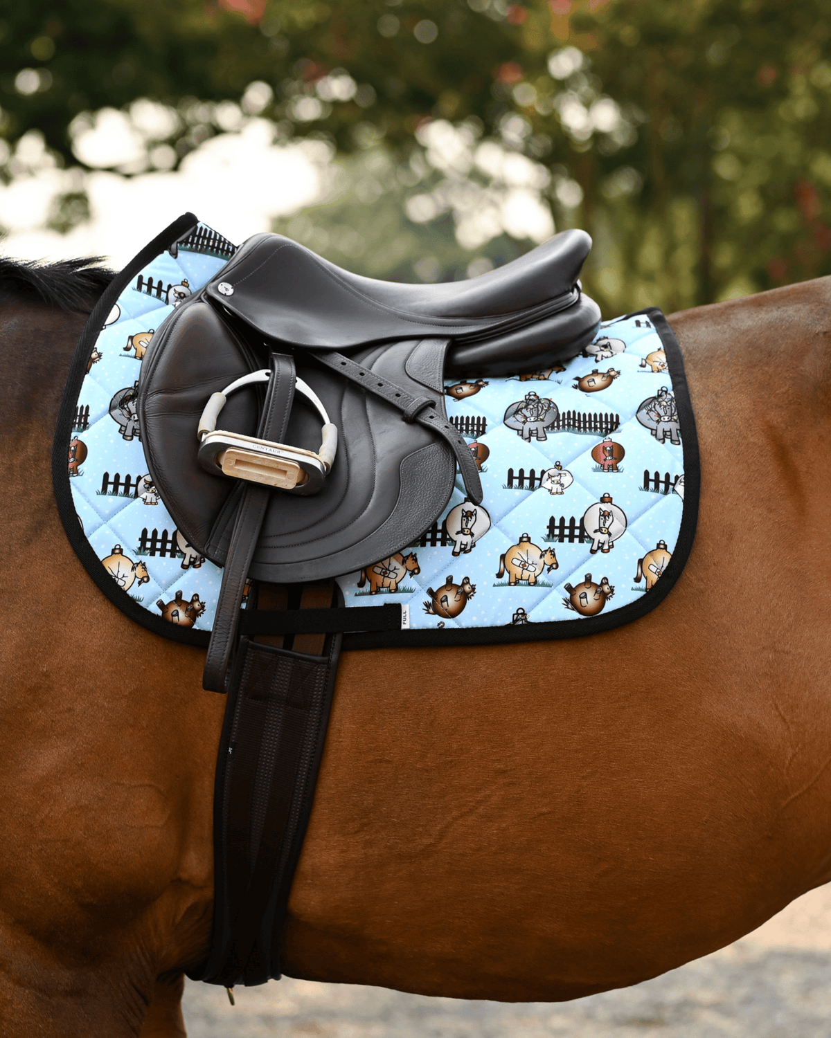 Pasture Ornaments holiday pad under a brown close-contact saddle, bauble horses on light blue quilting