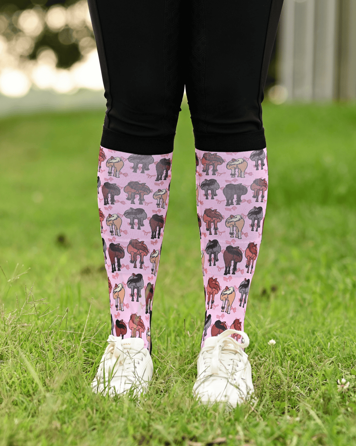 Red Ribbon Girlies boot socks seen from the front, pink ground scattered with horse hindquarters tied with red bows
