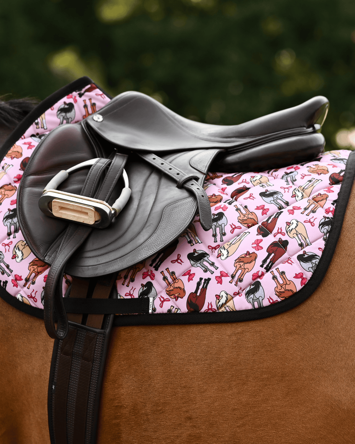 Light pink Red Ribbon Girlies pad under a brown close-contact saddle and stirrup, black binding