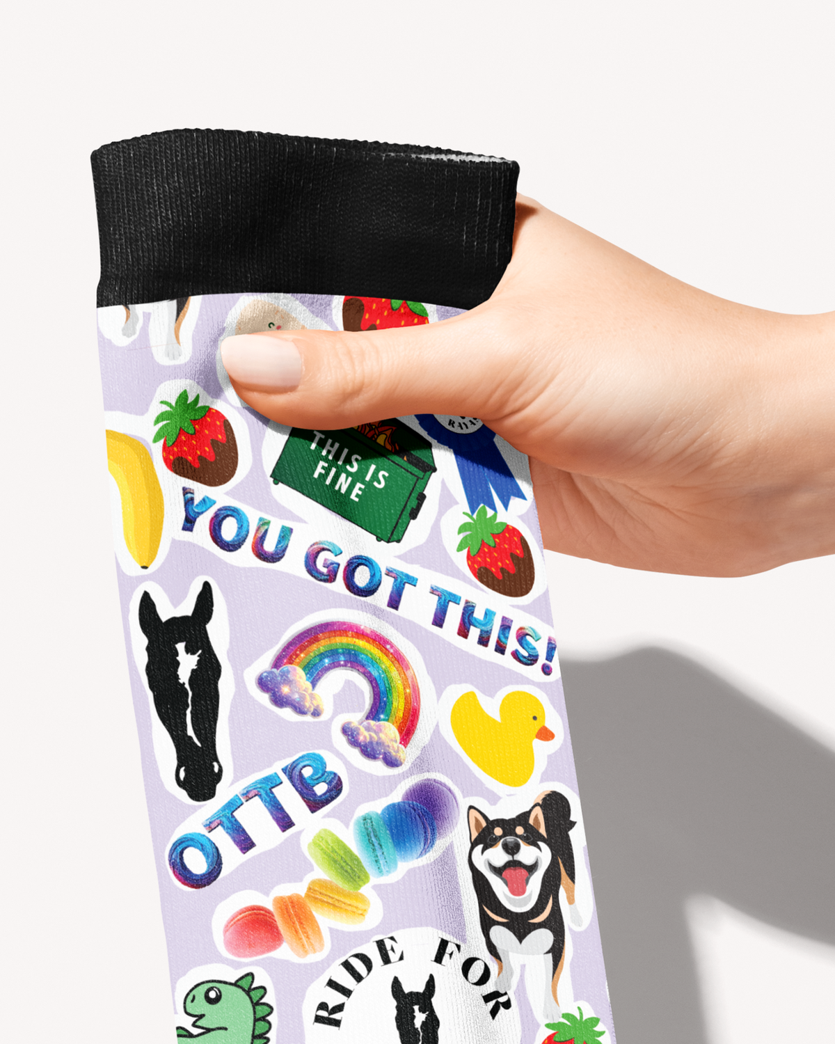 Friendship boot sock held by the black cuff, close-up of You Got This, OTTB, rainbow and rubber duck stickers